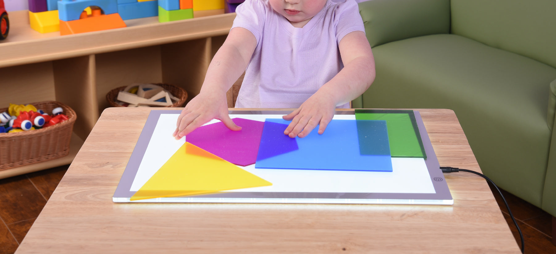 Children in classroom playing with colorful manipulatives on a light table