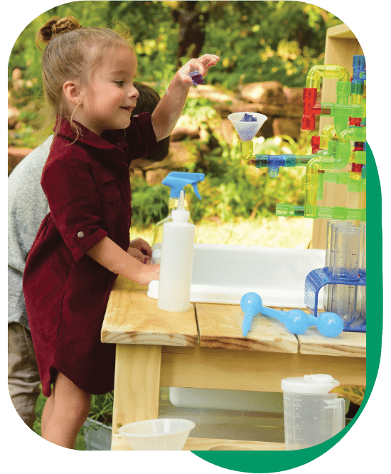 young girl standing at the Mud Kitchen and Outdoor Exploration Center playing with various materials