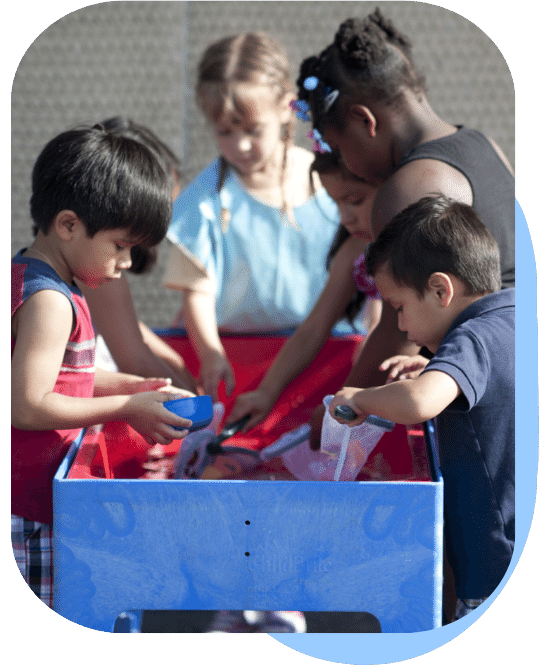 group of young children playing with various scoops and nets at a large water table outside