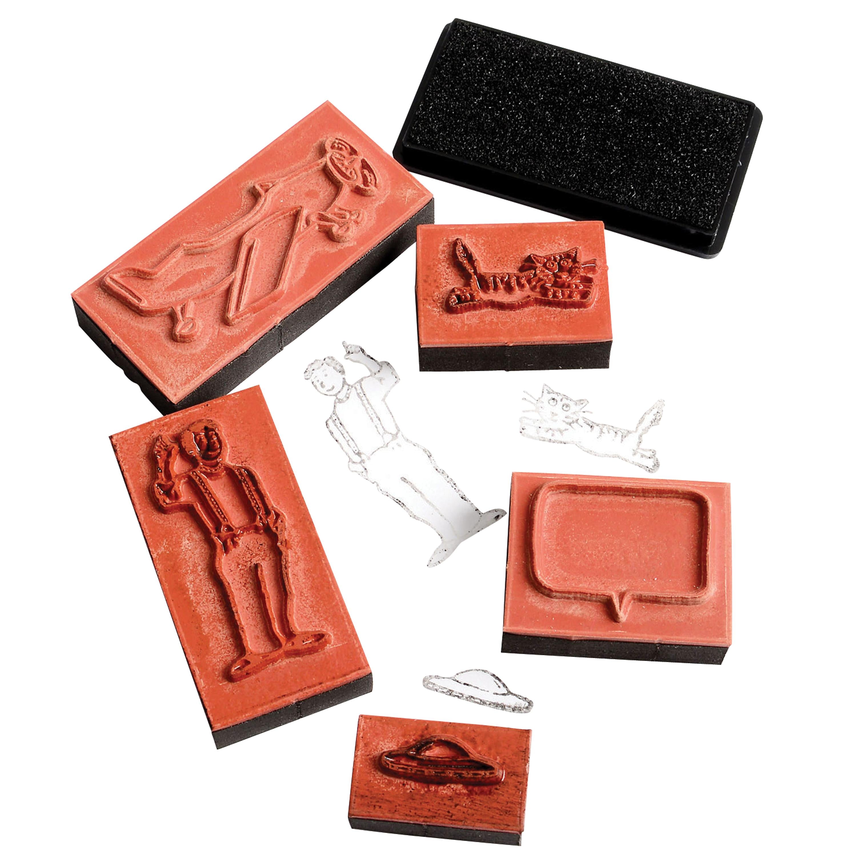 A set of rubber stamps and carving blocks in terracotta red with black bases, shown on a white background. The set includes various shapes and designs, including a figure, a grapevine, a speech bubble, and a UFO, along with two clear acrylic templates and a black textured block.
