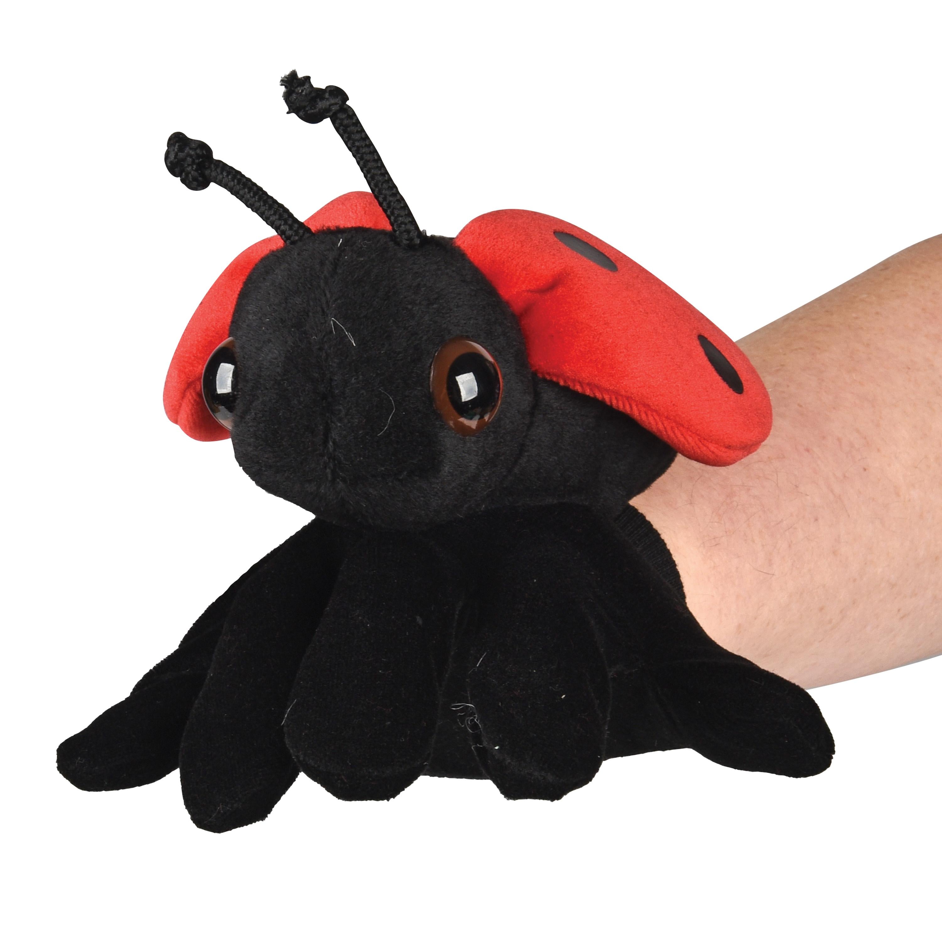 Plush ladybug toy held by a hand on a white background