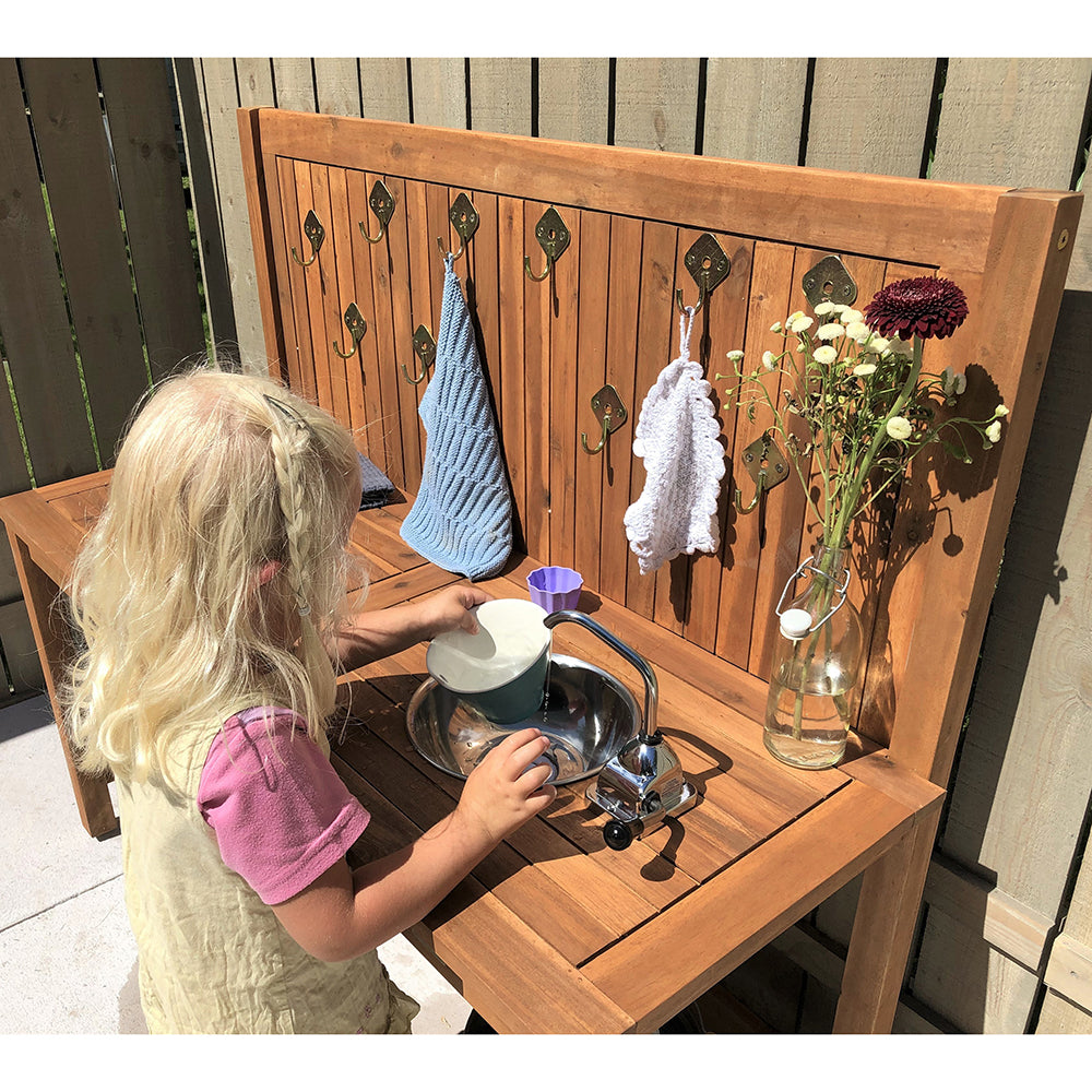 Child playing with a wooden outdoor play kitchen set.