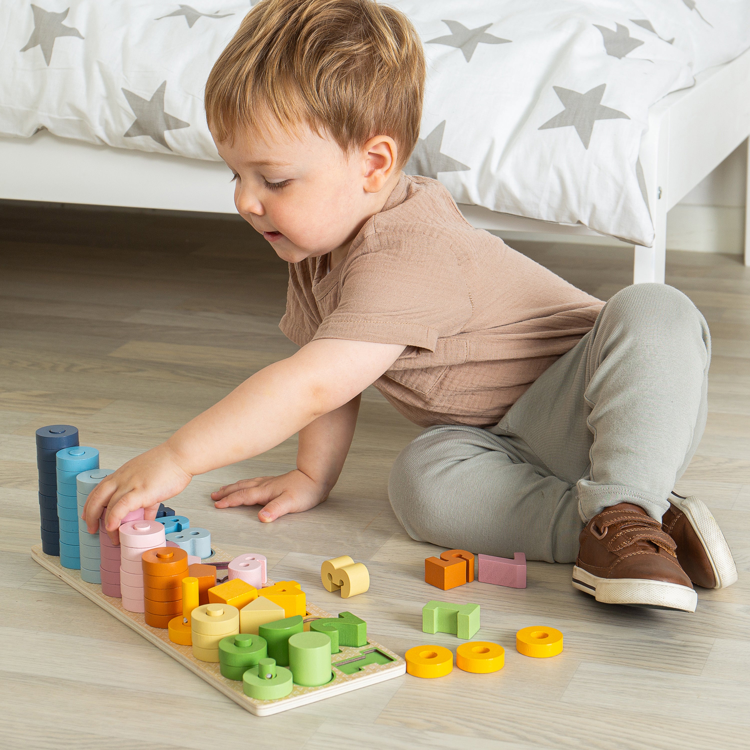 Child playing with colorful wooden blocks on a wooden floor.