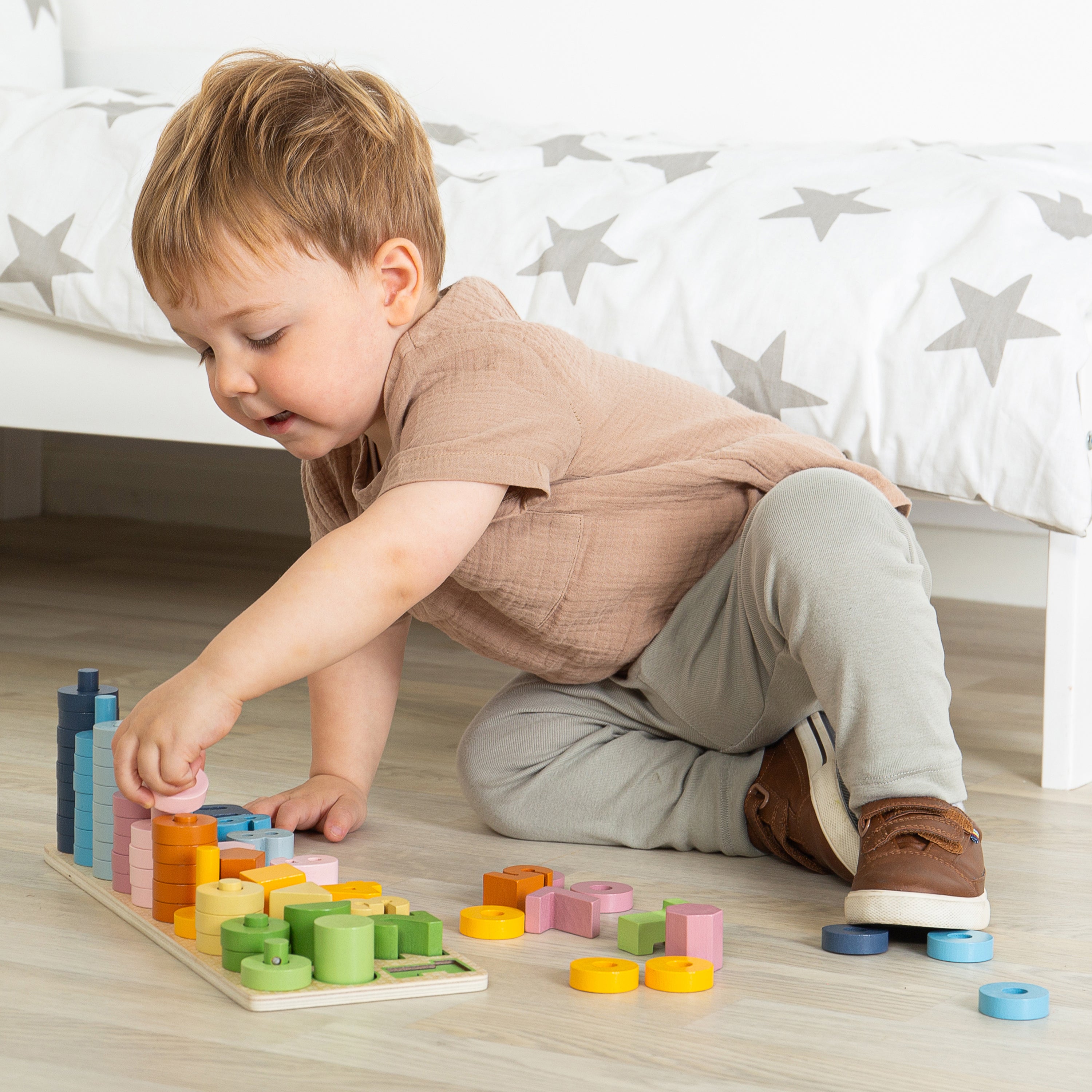 Child playing with colorful wooden blocks on a wooden floor.