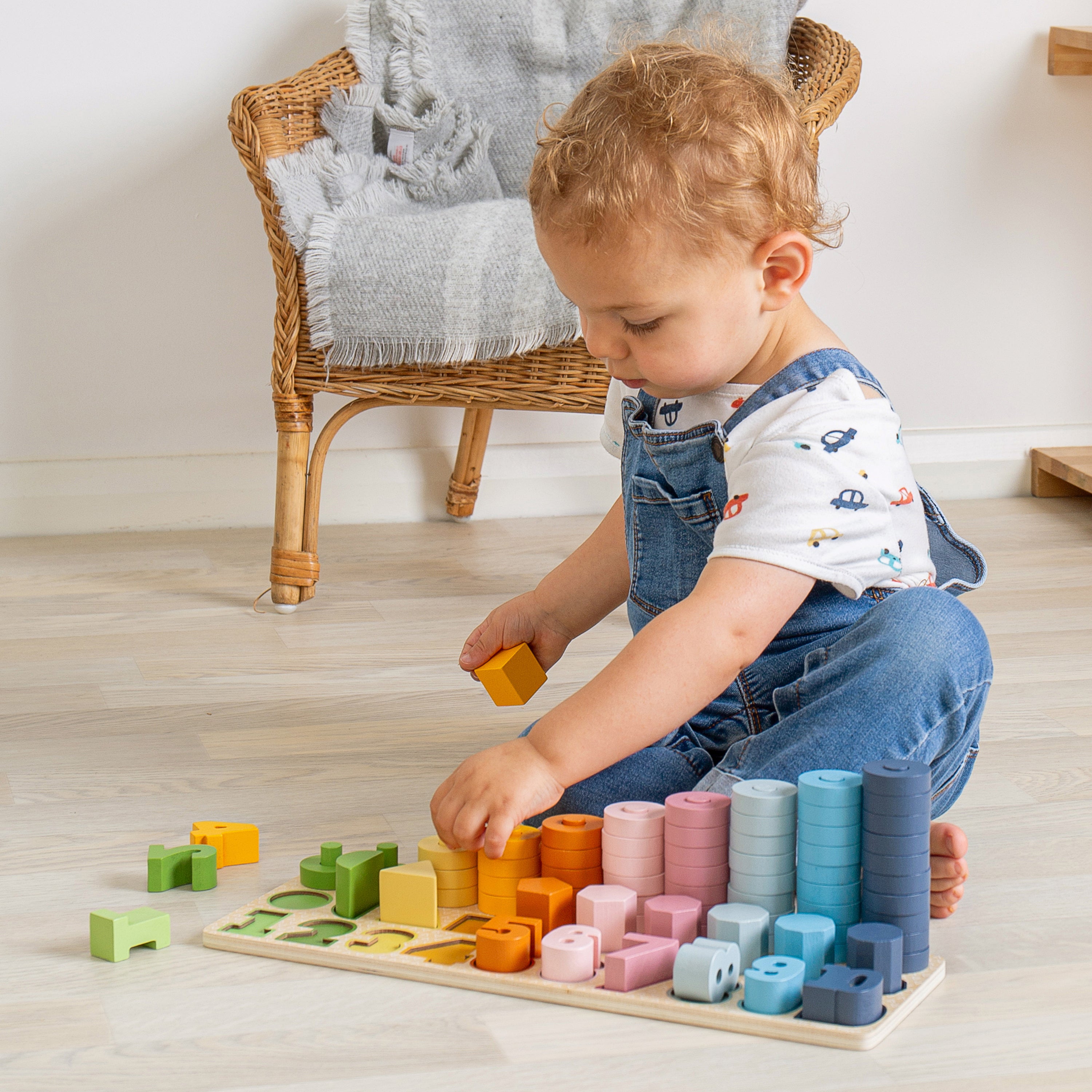 Child playing with colorful wooden blocks on a wooden floor.