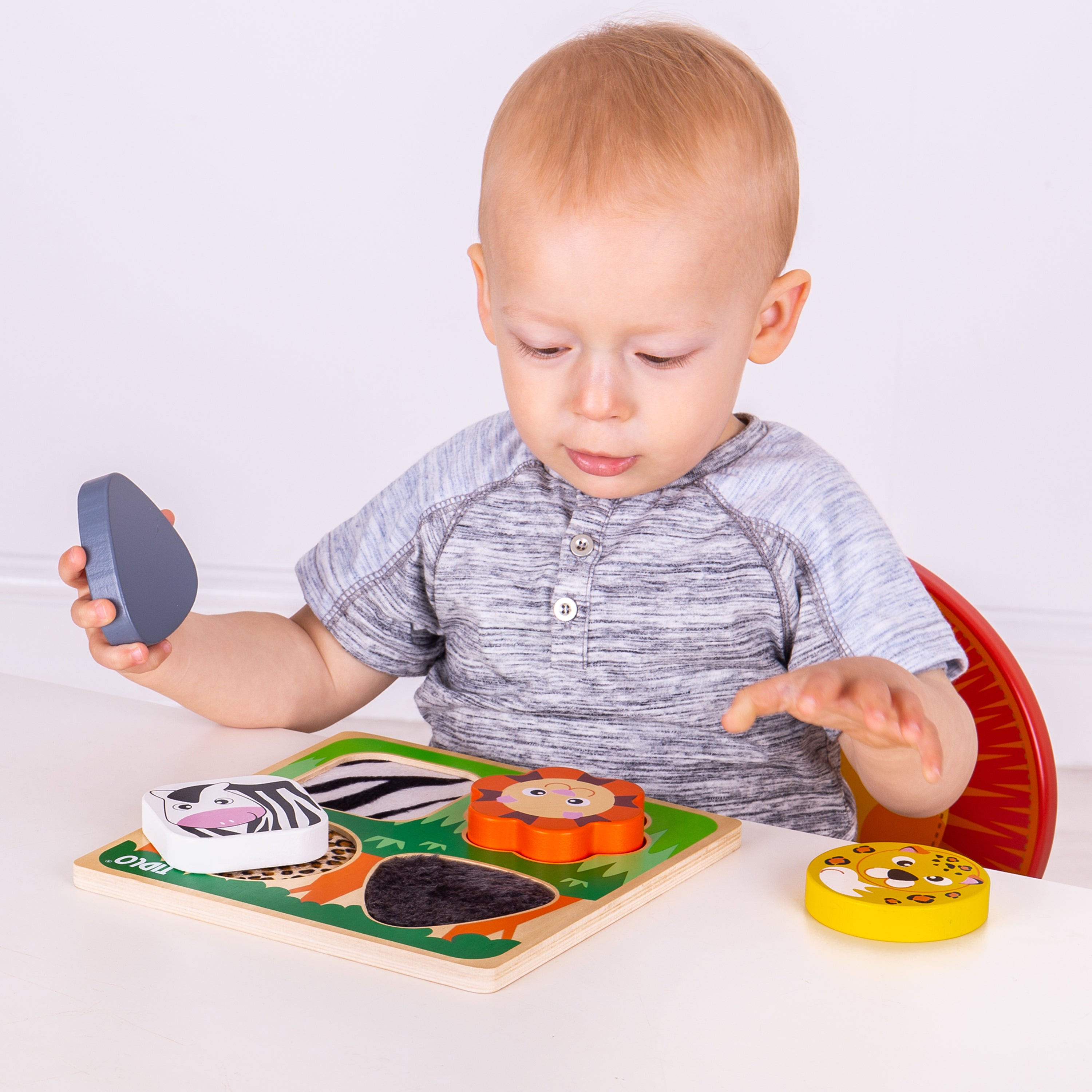 Child playing with a wooden puzzle toy on a white surface