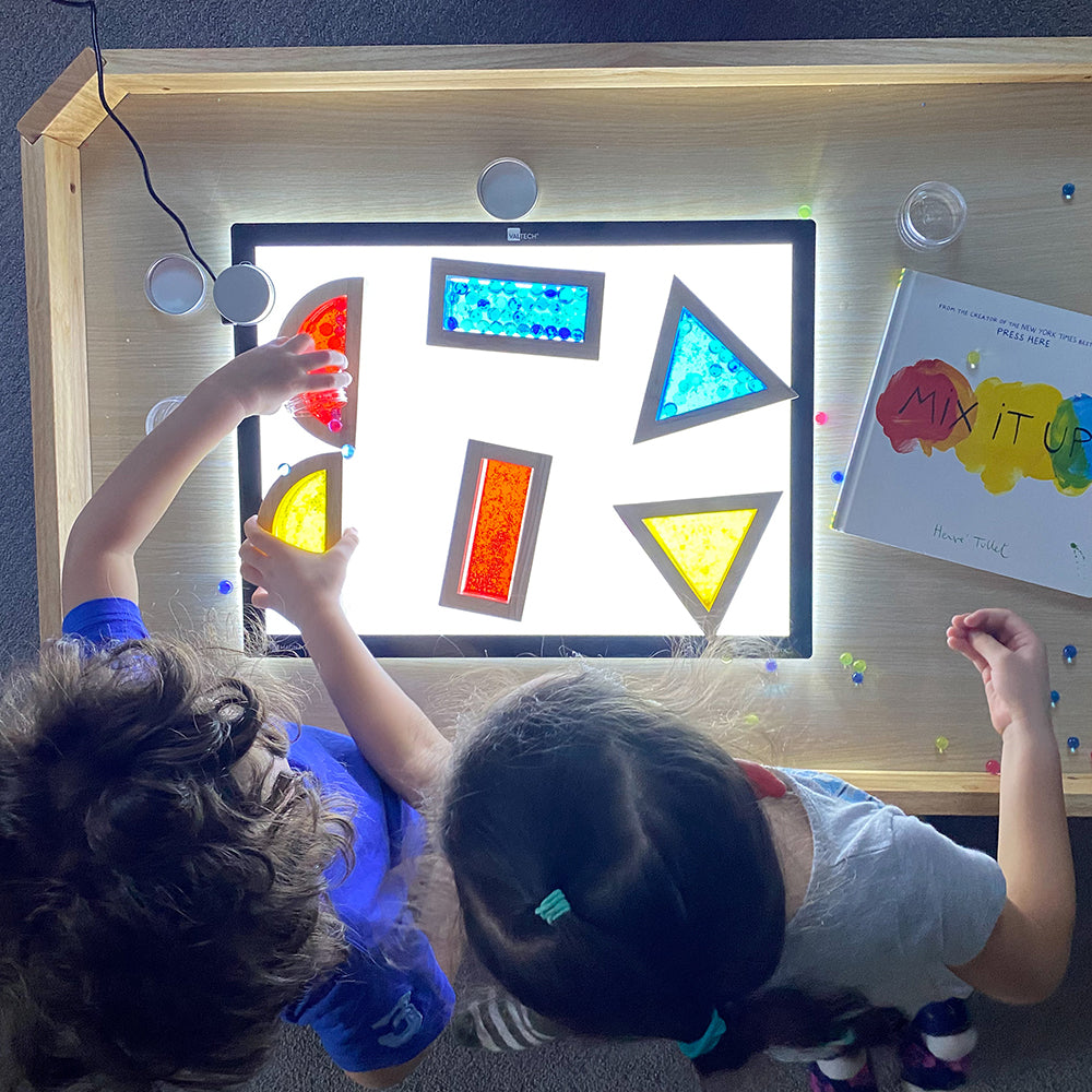 Kids using transparent water blocks on light table