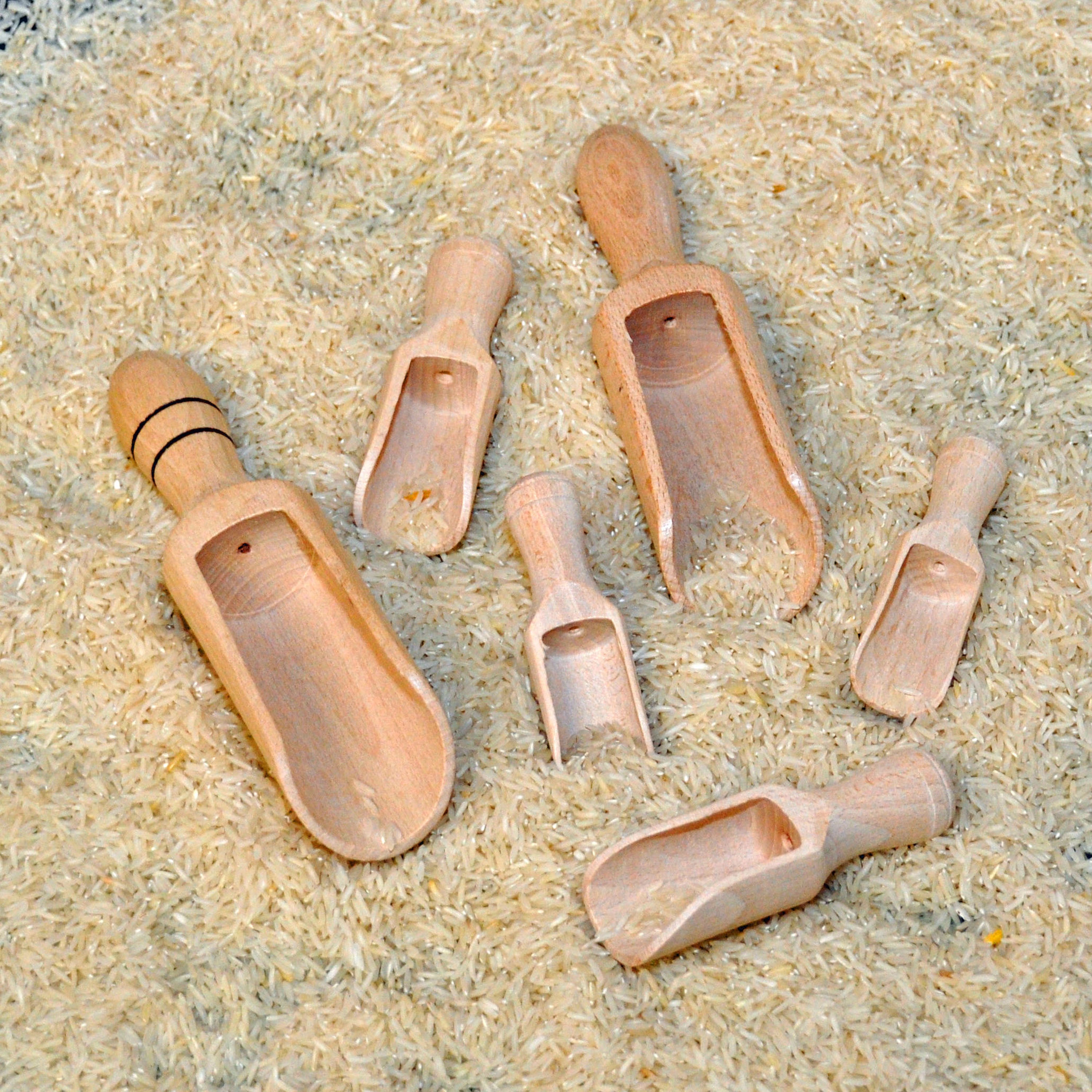 Set of wooden scoops on a sandy surface