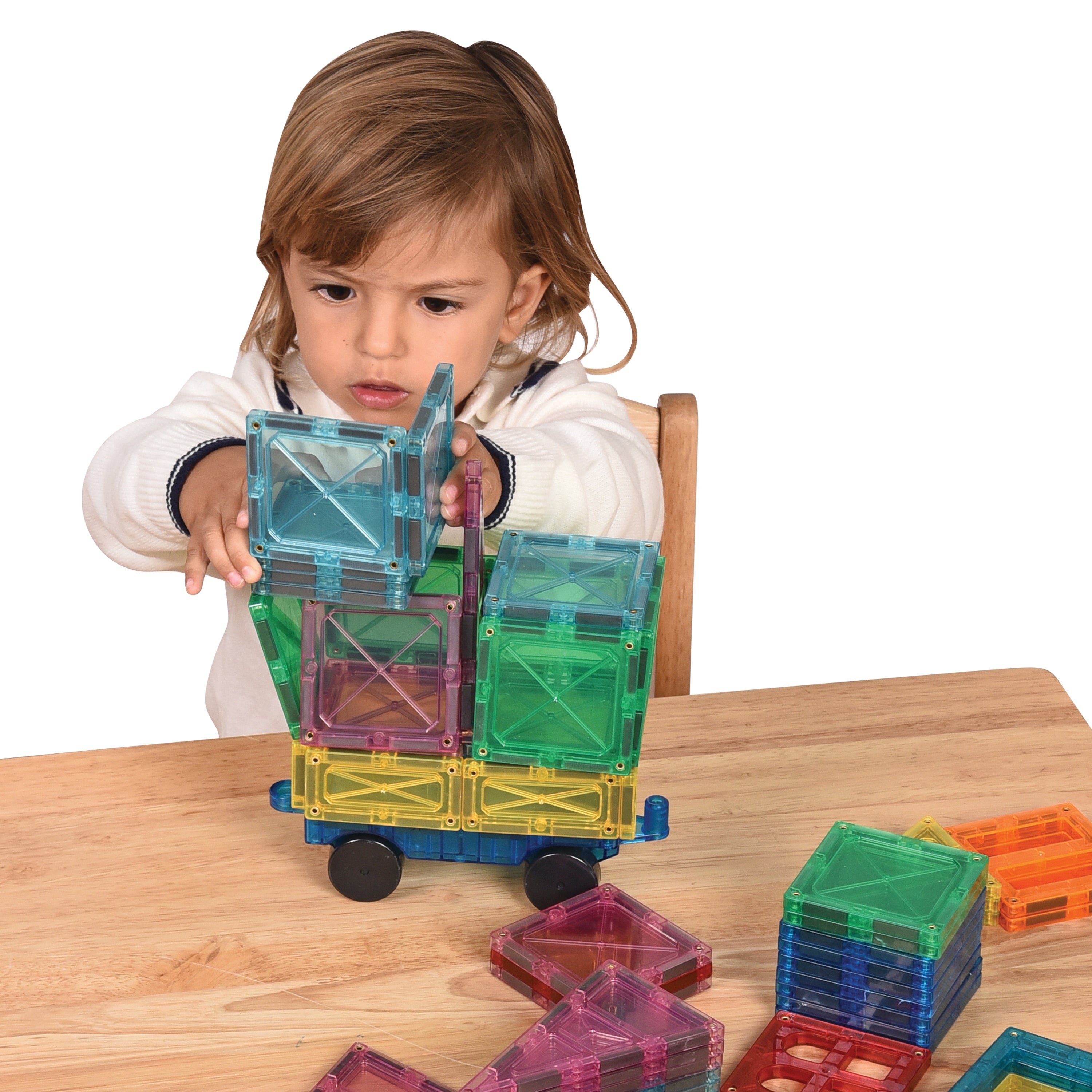 Child playing with colorful magnetic building blocks on a wooden table.