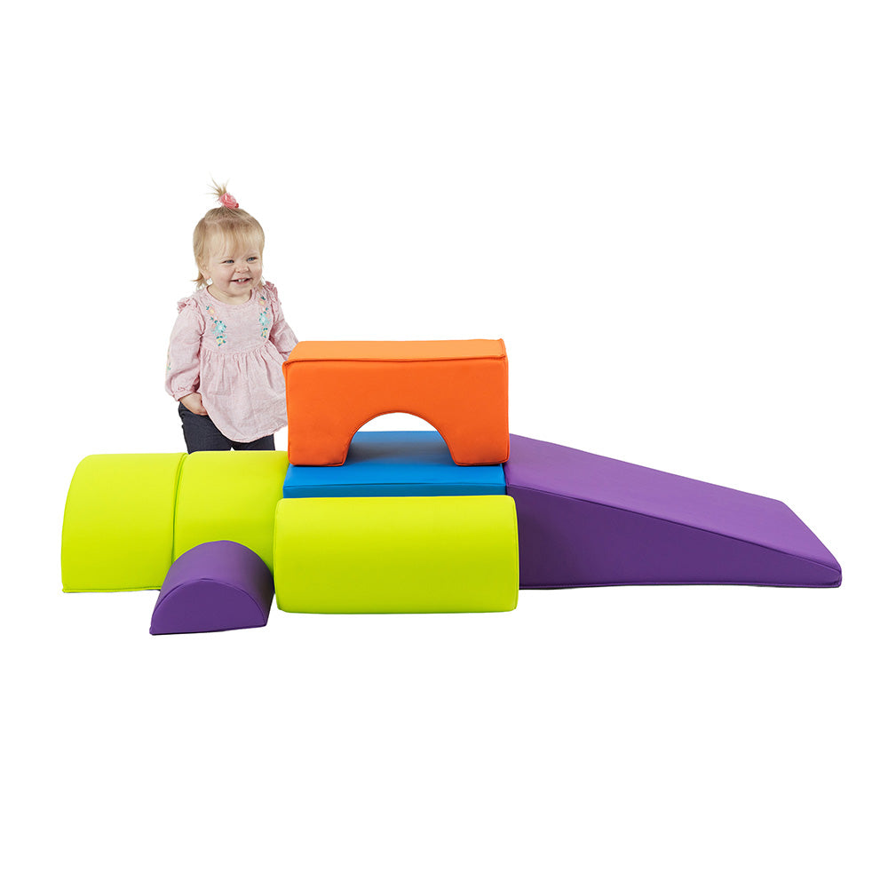 Colorful soft play structure with a child standing next to it on a white background
