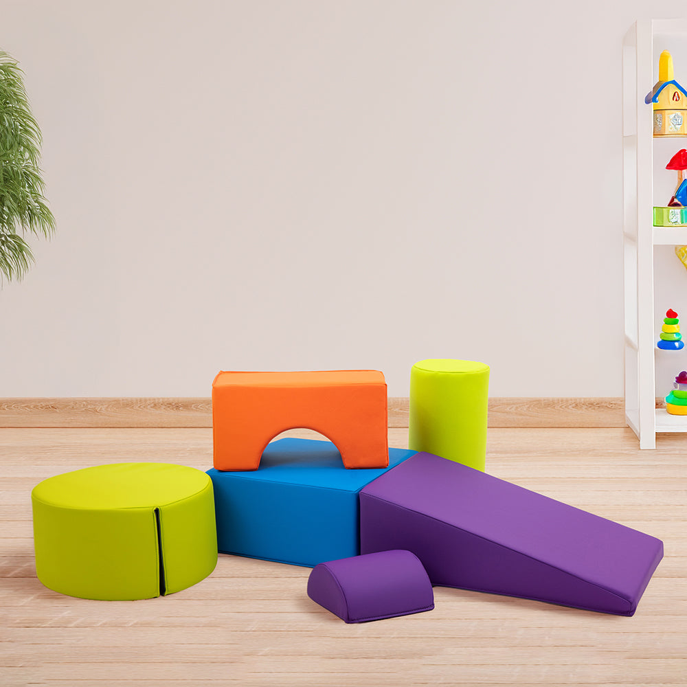 Colorful foam blocks on a wooden floor with a child's play area in the background.