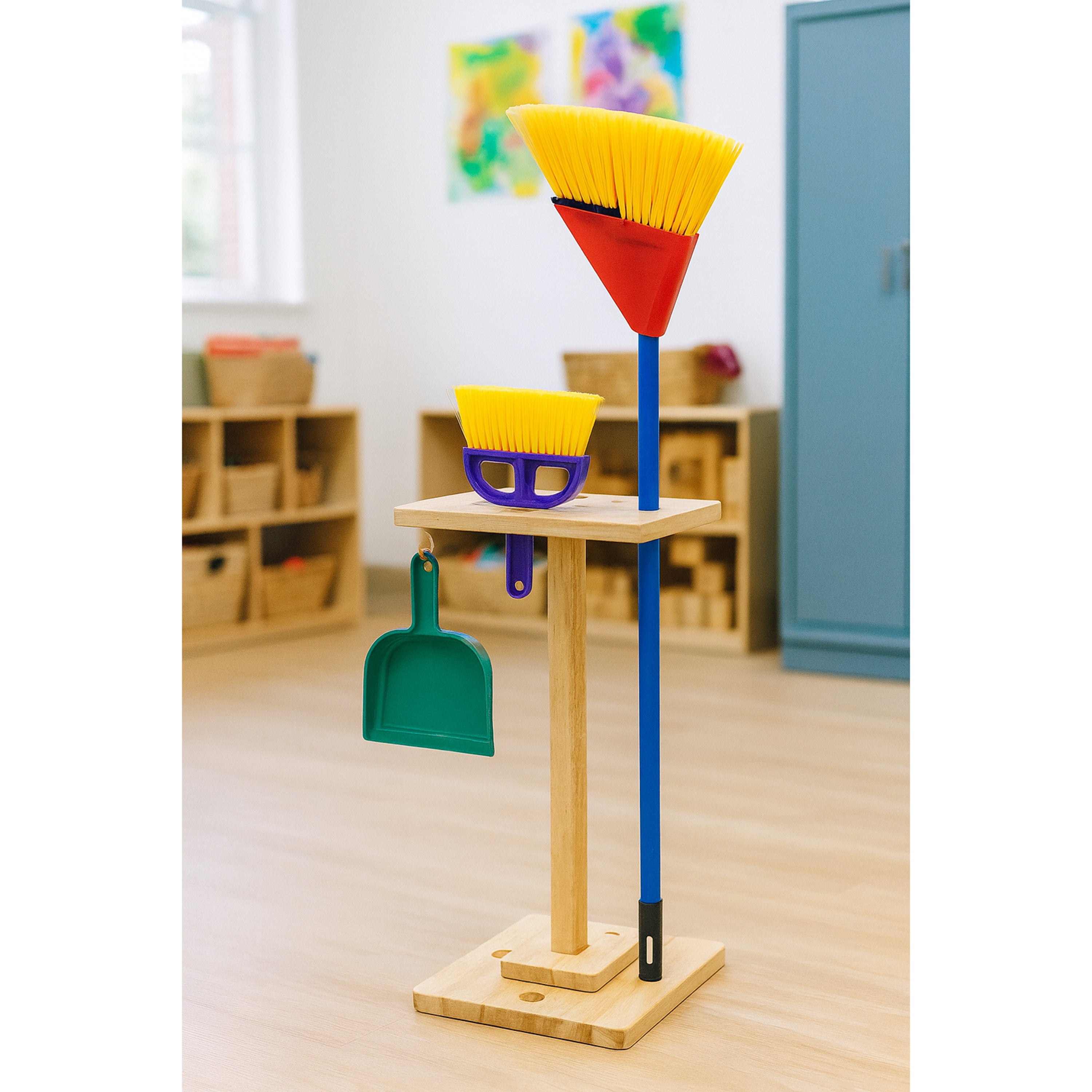 Colorful broom, dustpan, and scoop set on a stand in a classroom setting.