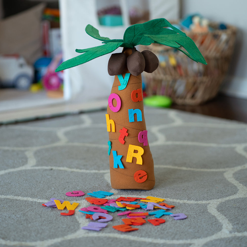 A fabric tree playset with letters adhered to it, set on a classroom carpet, part of the Chicka Chicka Boom Boom series.