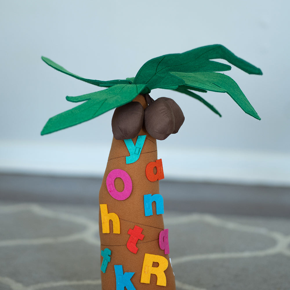 A fabric tree playset with letters adhered to it, set on a classroom carpet, part of the Chicka Chicka Boom Boom series.