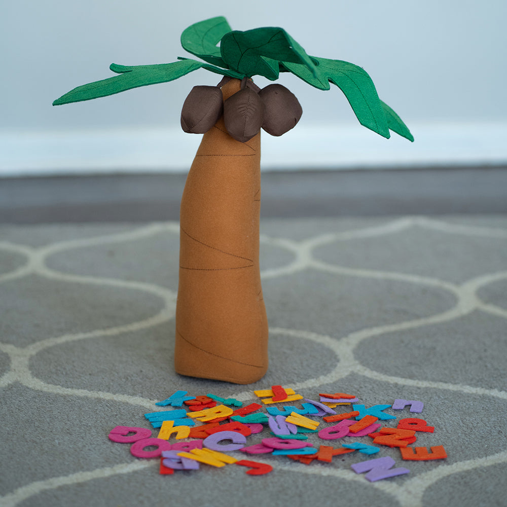 A fabric tree playset with letters adhered to it, set on a classroom carpet, part of the Chicka Chicka Boom Boom series.