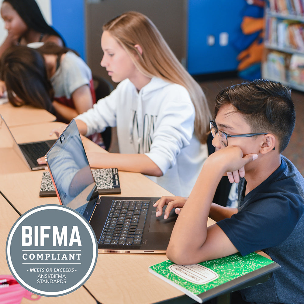 Students using laptops in a classroom with a BIFMA compliant label.