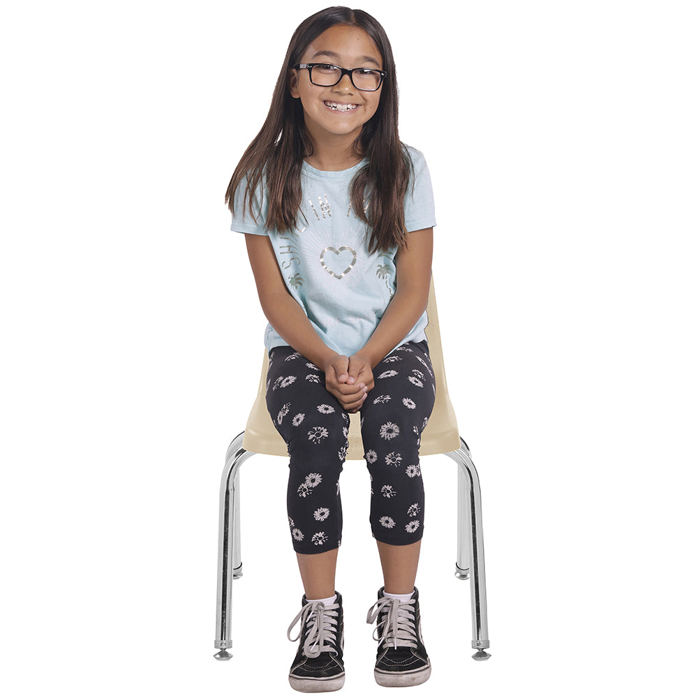 Young girl sitting on a chair wearing glasses, a light blue shirt, and dark floral leggings.