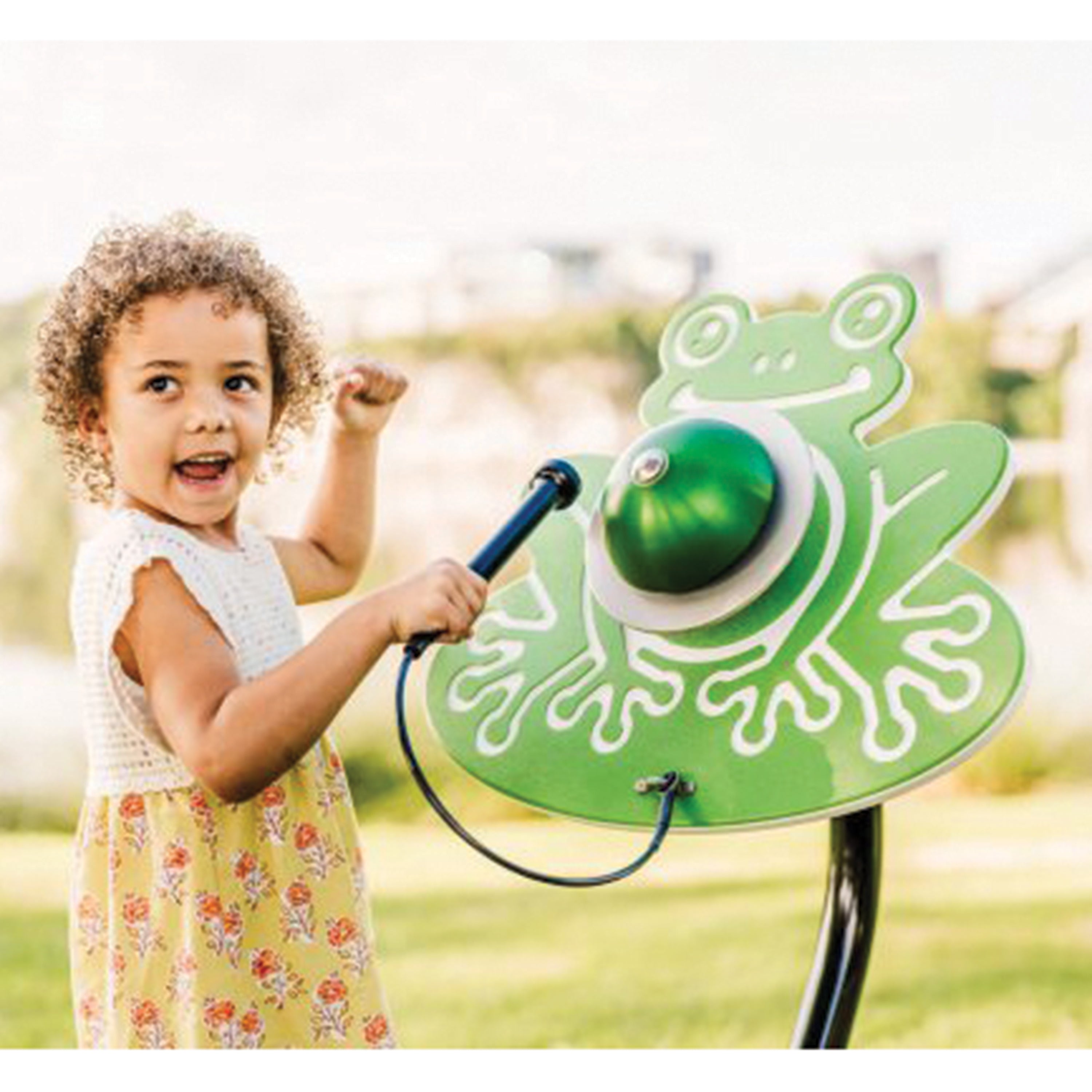 Child playing with a green frog-shaped outdoor toy in a park