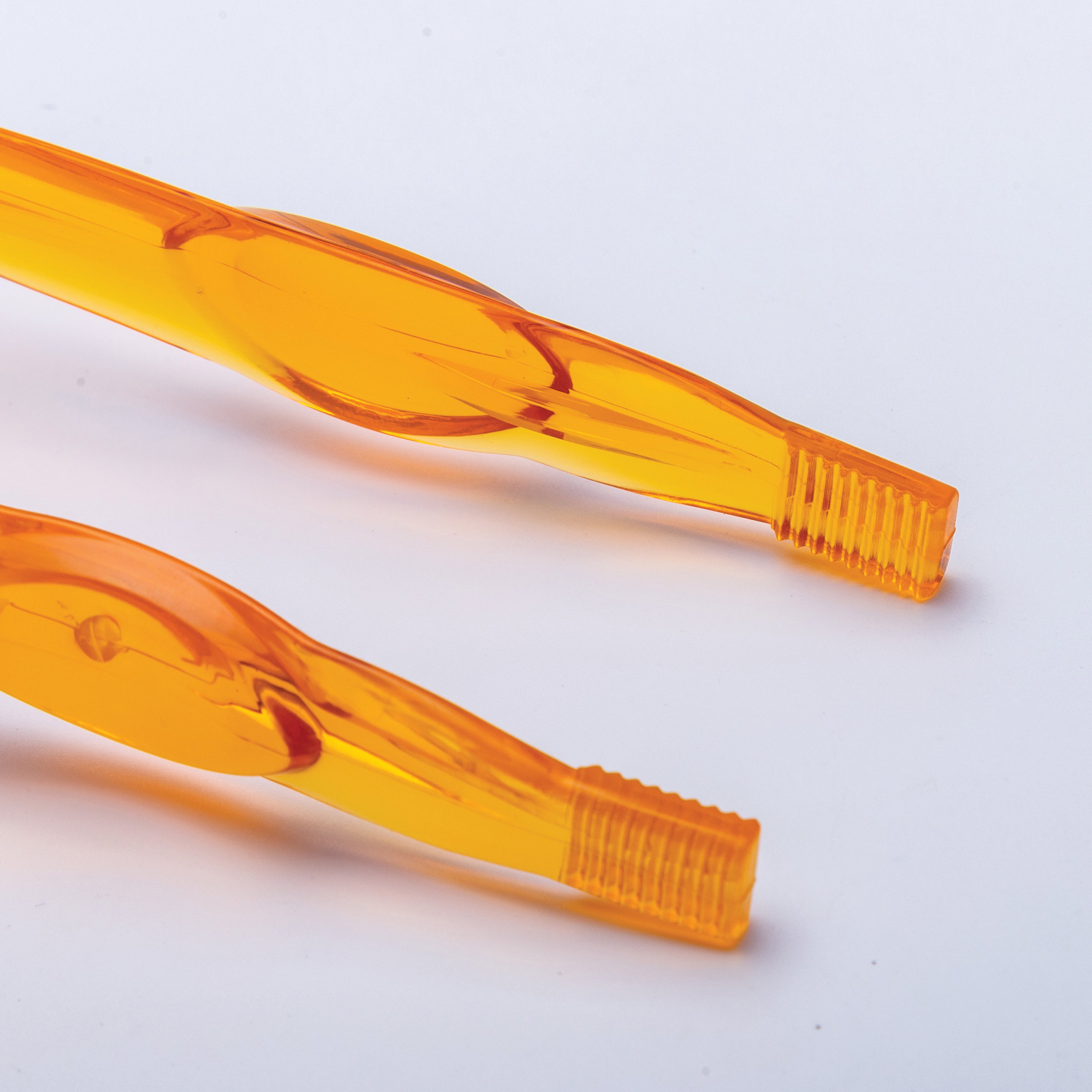 Two orange plastic tweezers on a white background