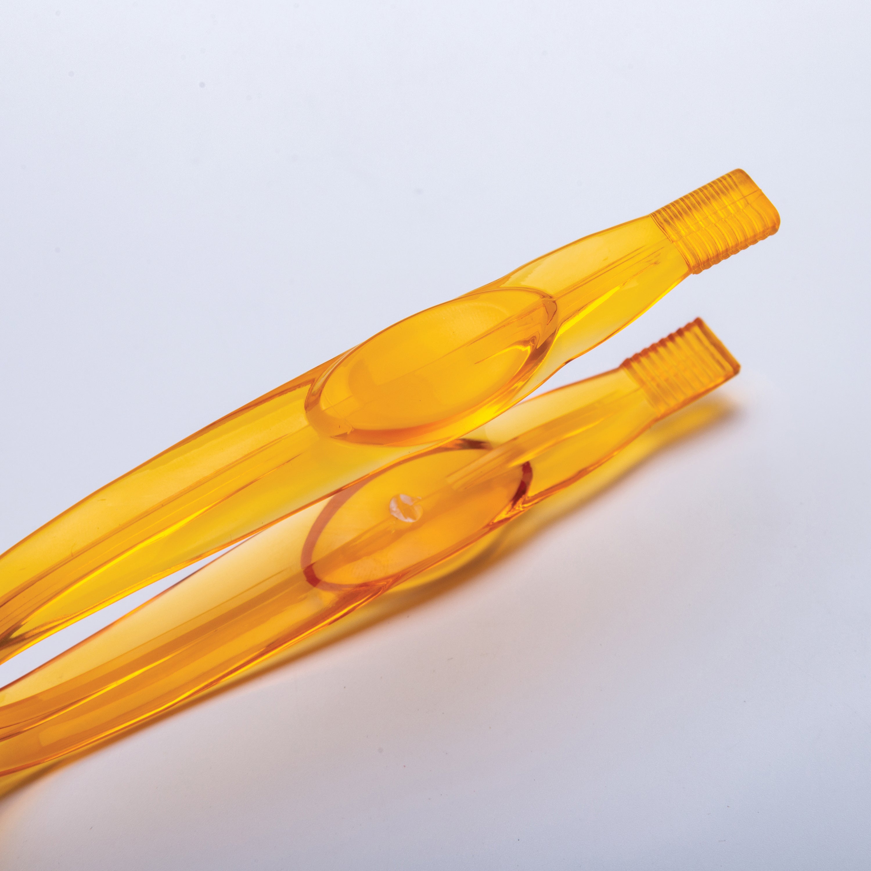 Two orange tweezers on a light gray background