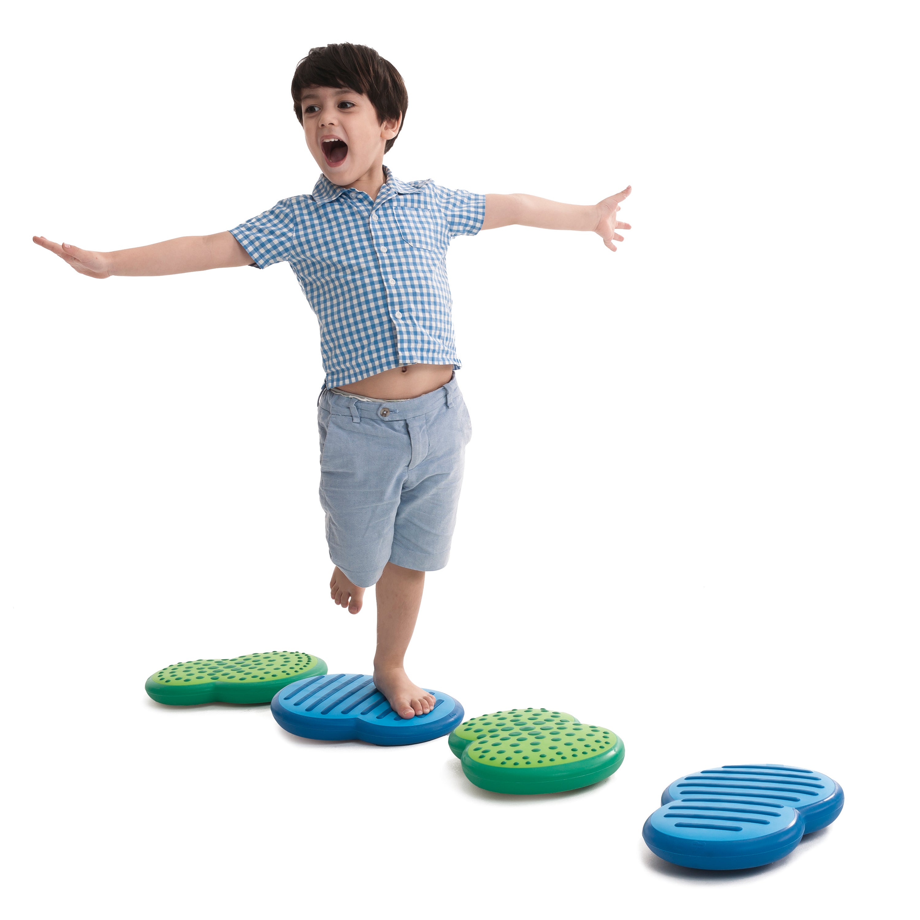 Child standing on a set of blue and green balance steps against a white background