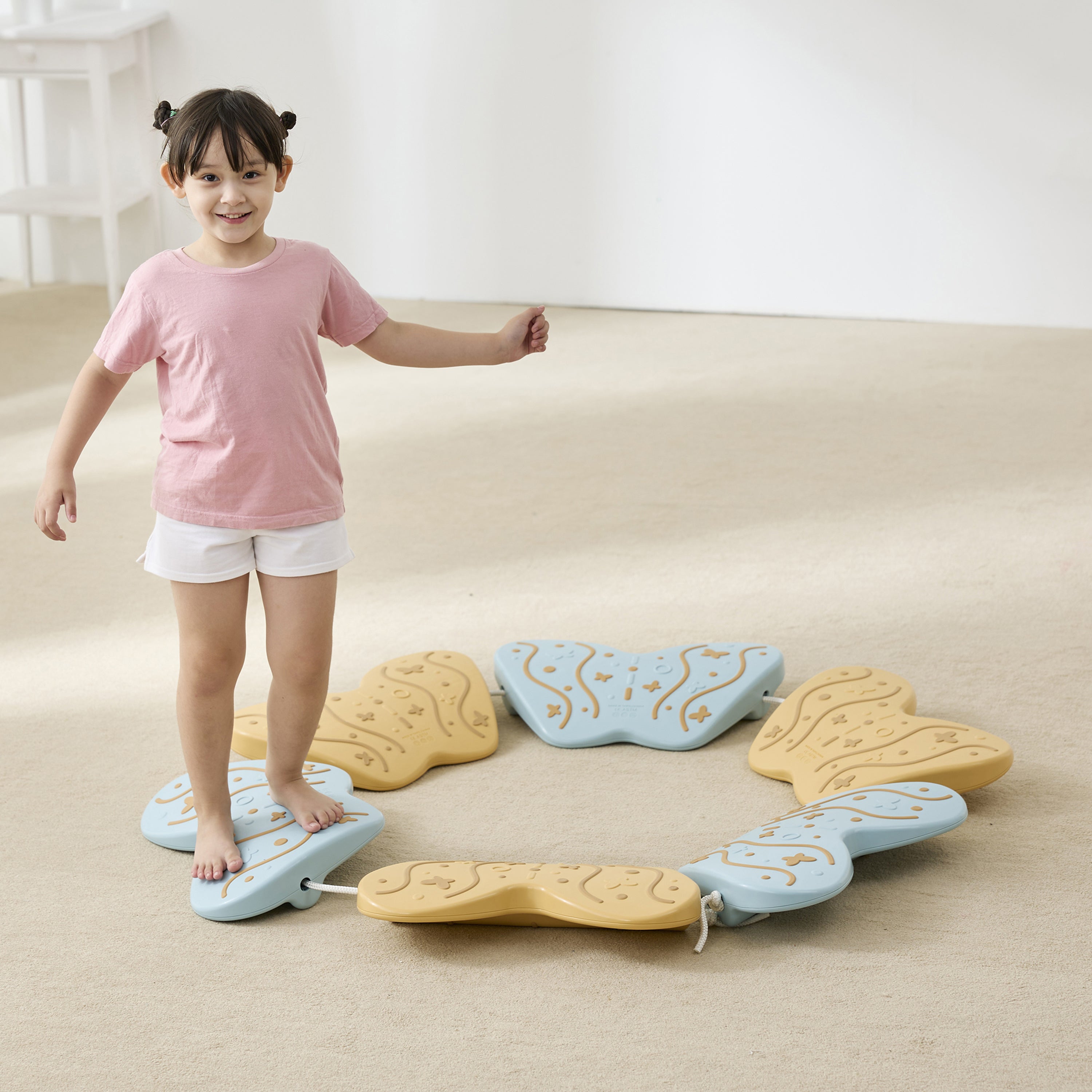 Child standing on a colorful balance board on a beige carpet