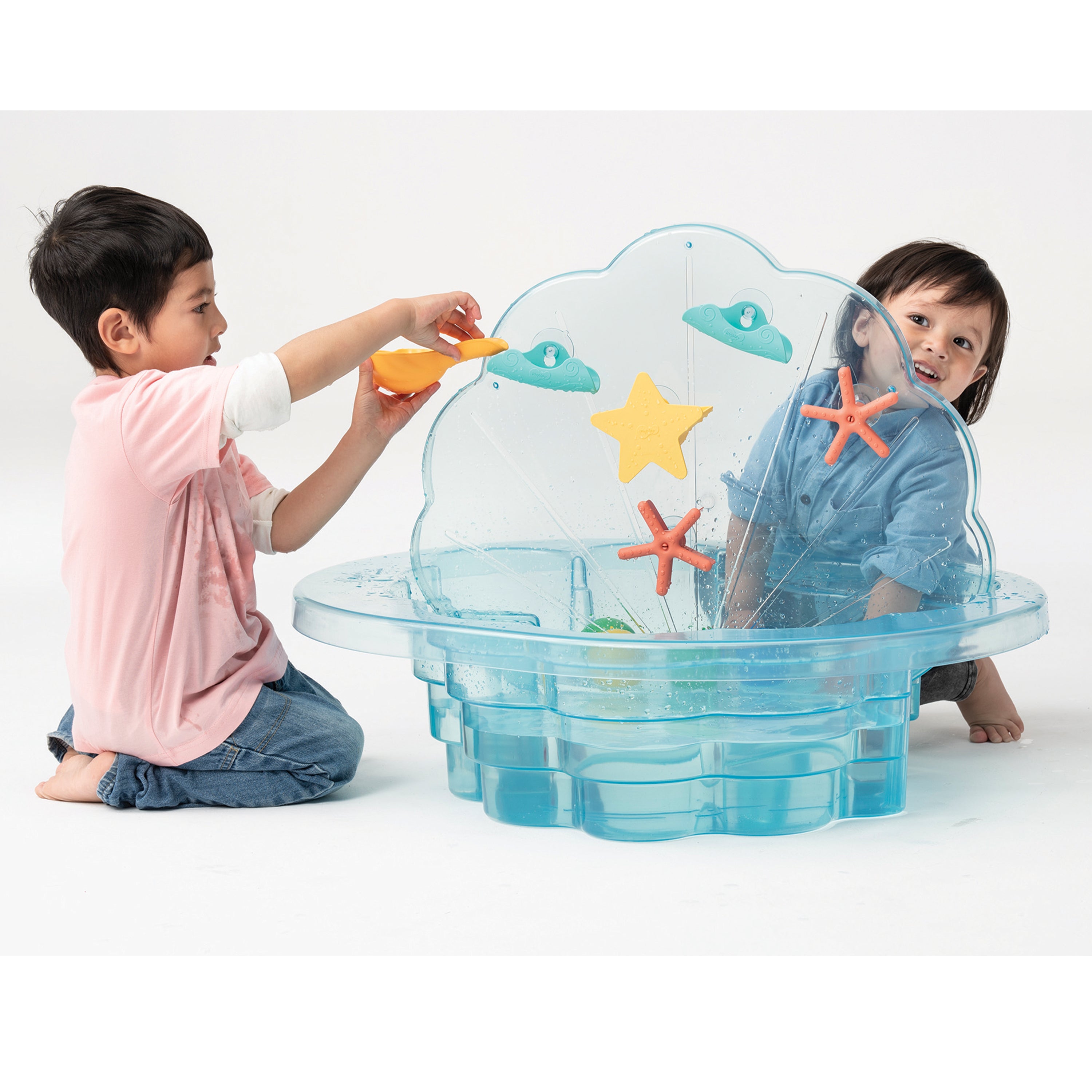 Two children playing with a transparent clam-shaped toy on a white background