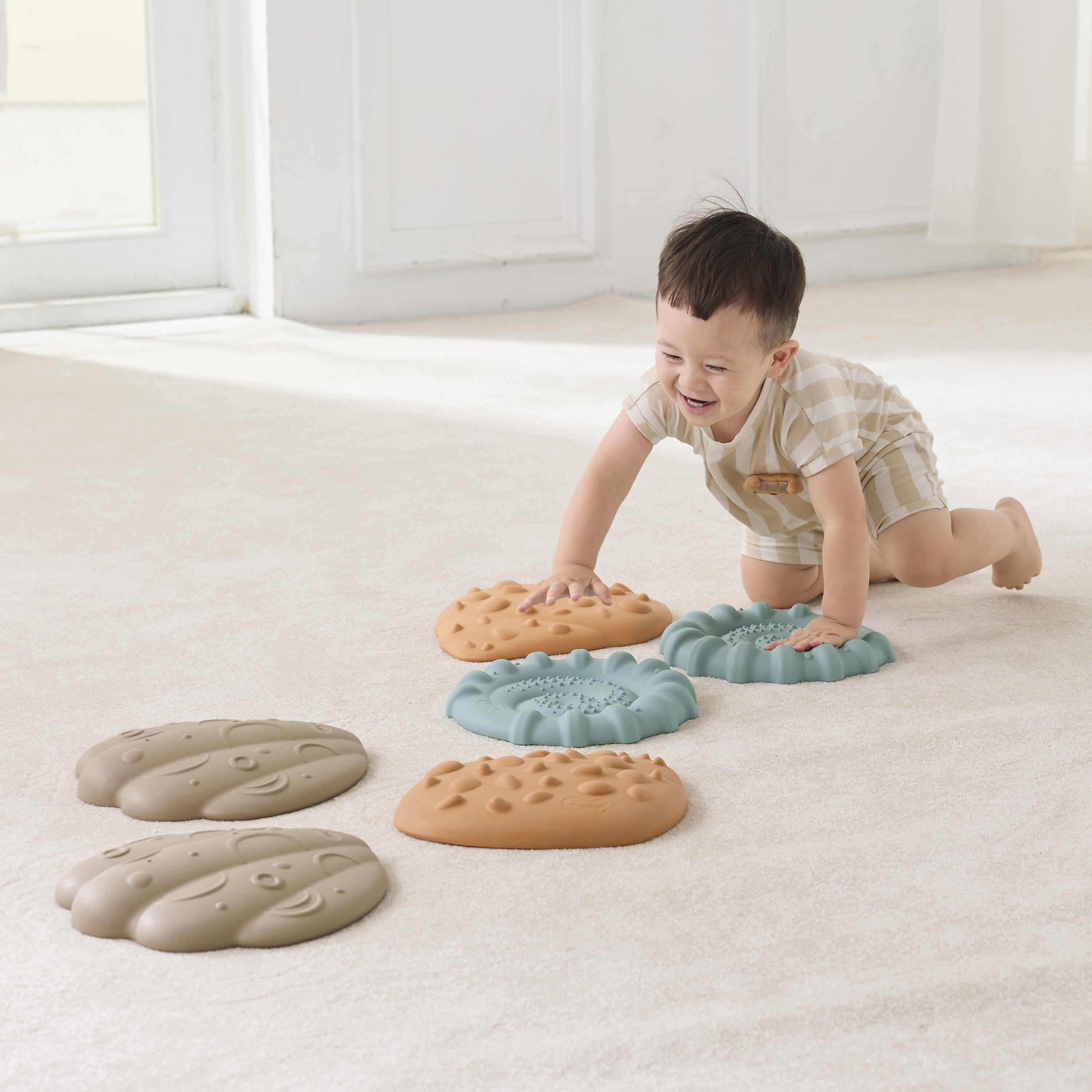 Child playing with colorful tactile shells on a light-colored floor.