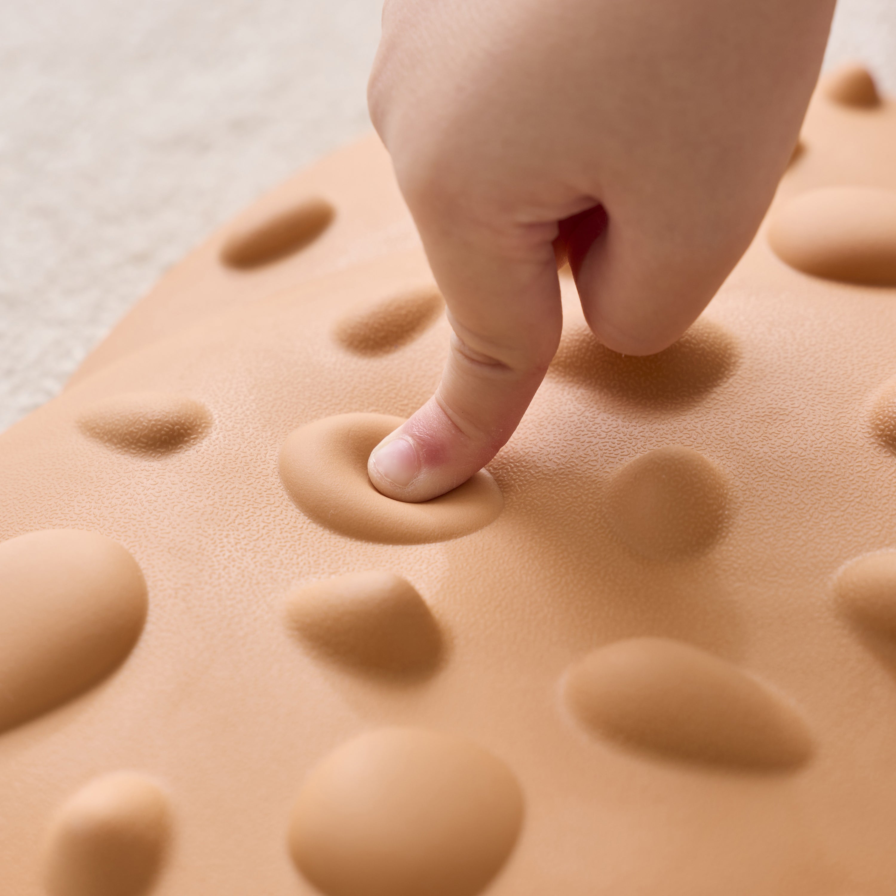 Hand pressing into a textured beige surface