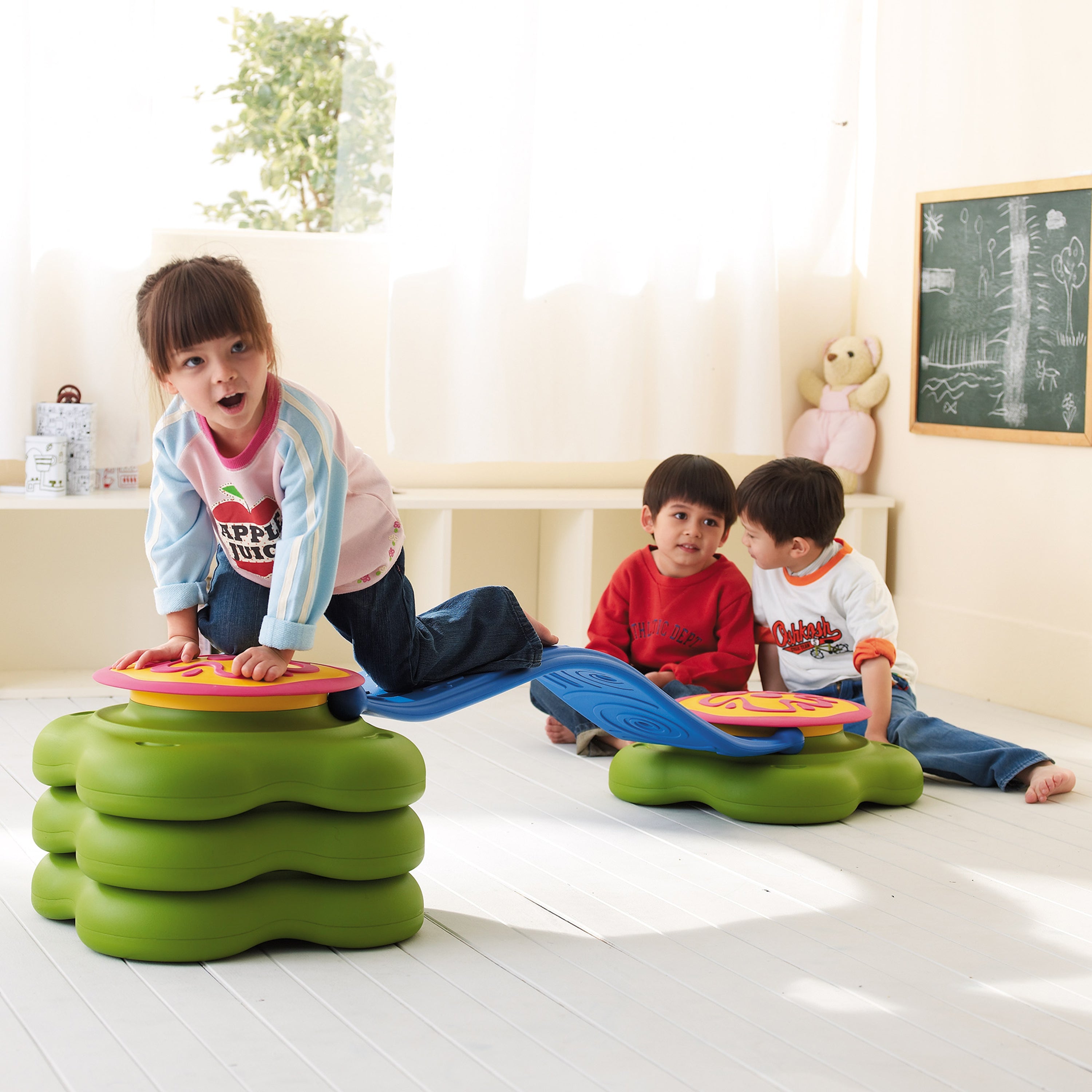 Children playing with colorful step stools in a classroom setting.