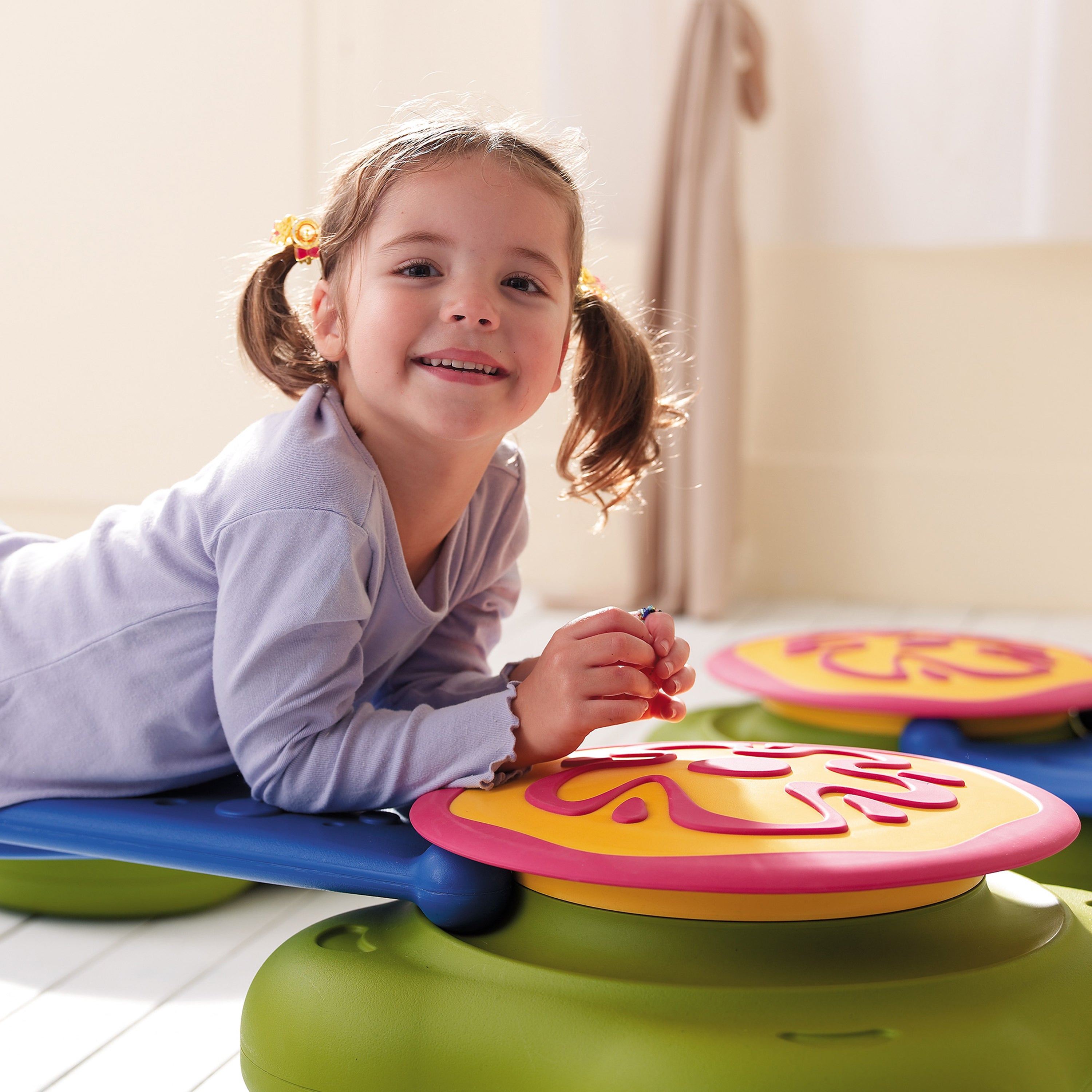Child playing on a colorful balance board with a neutral background