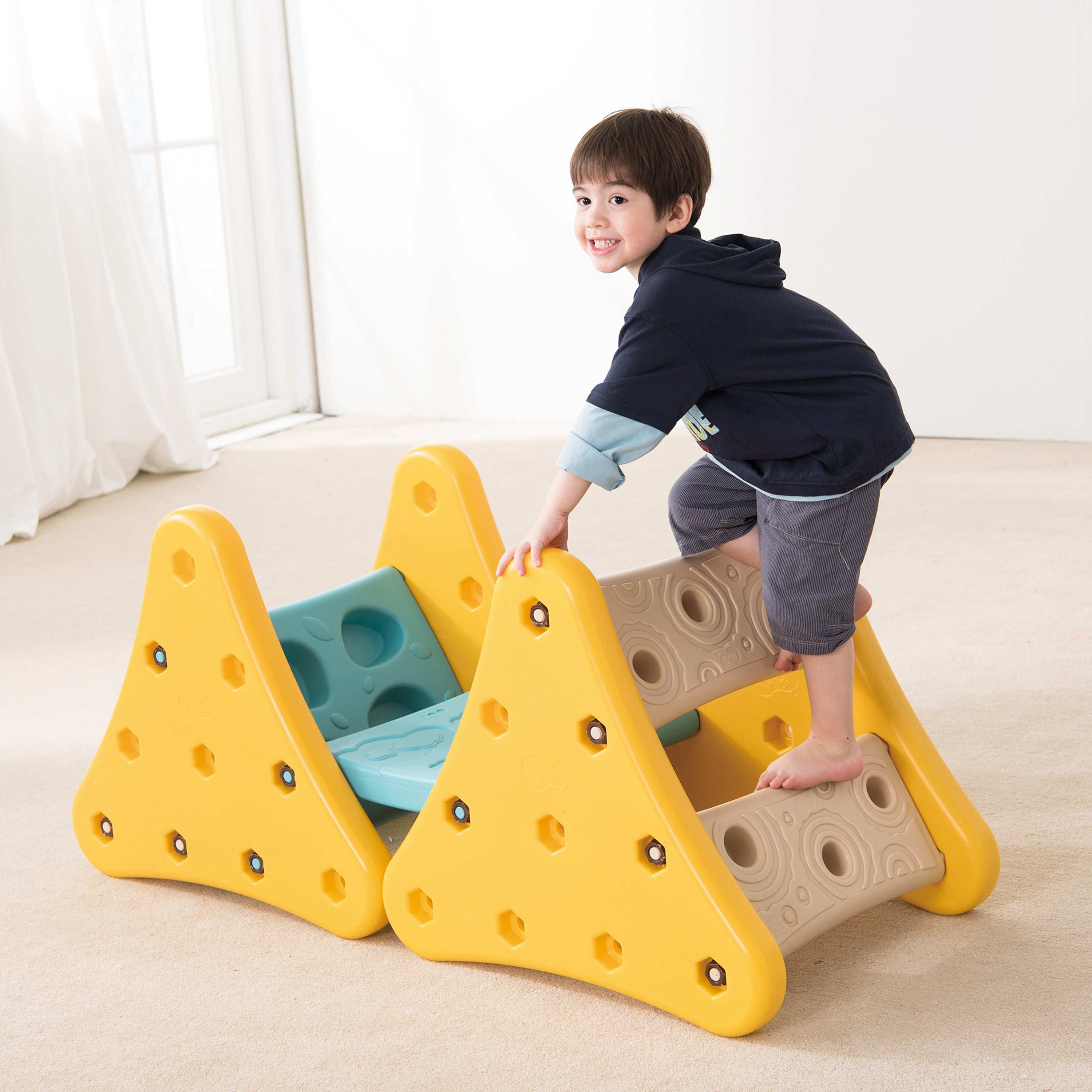 Child playing on a yellow climbing toy indoors
