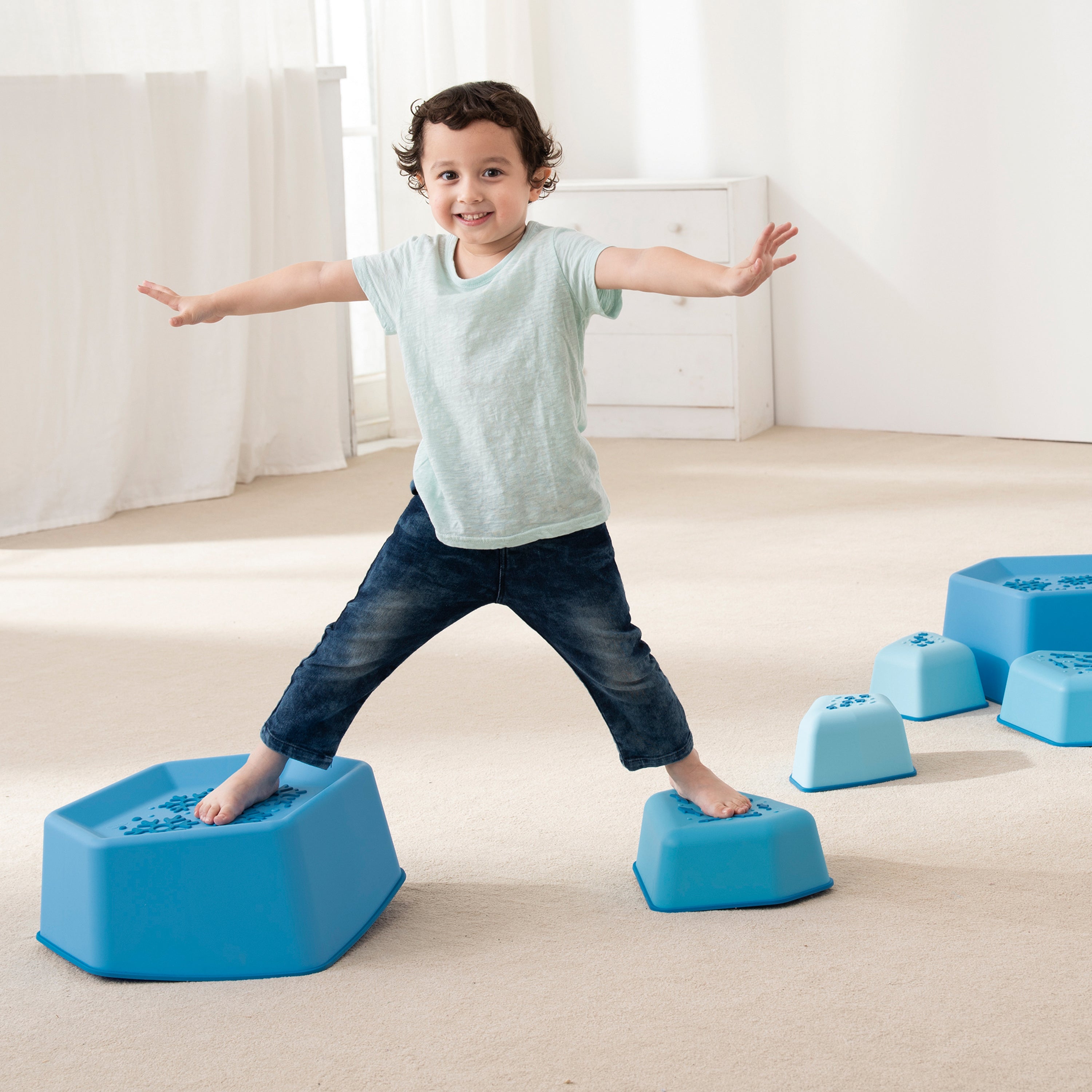 Child balancing on blue foam blocks in a bright room