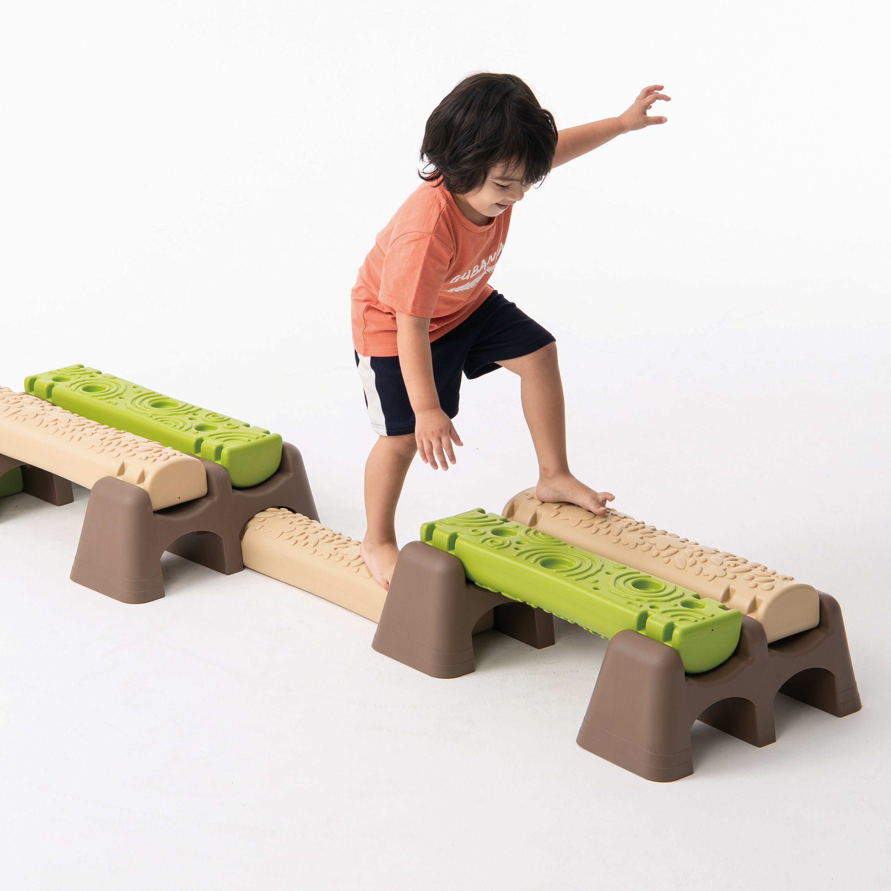 Child playing with a set of green and beige stepping stones on a white background
