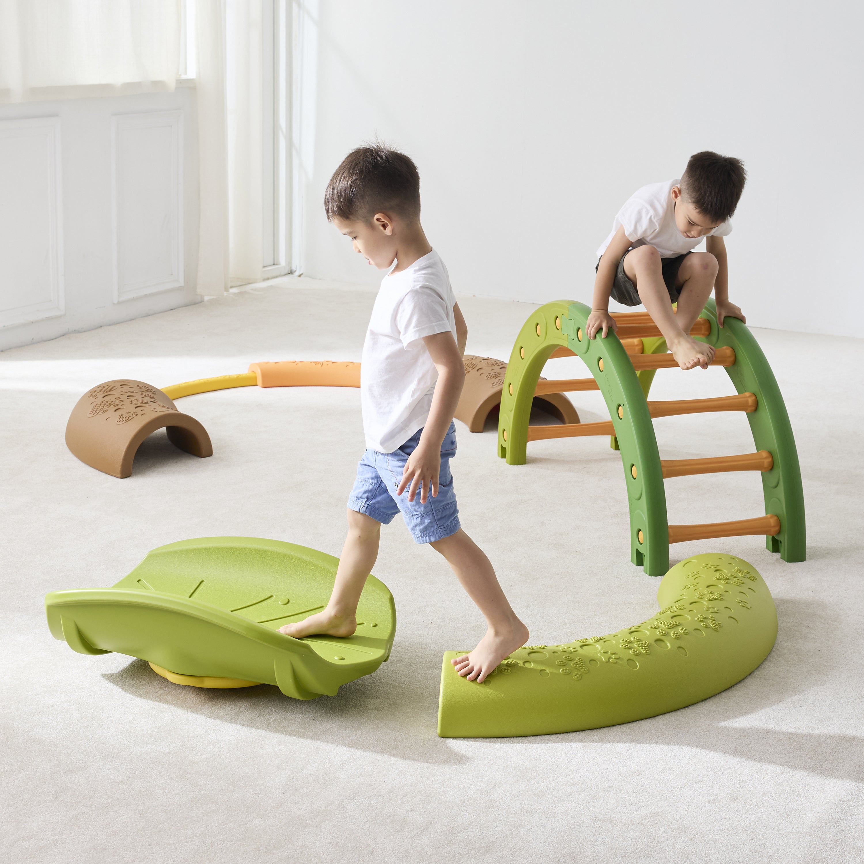 Two children playing on a green play structure in a bright room.