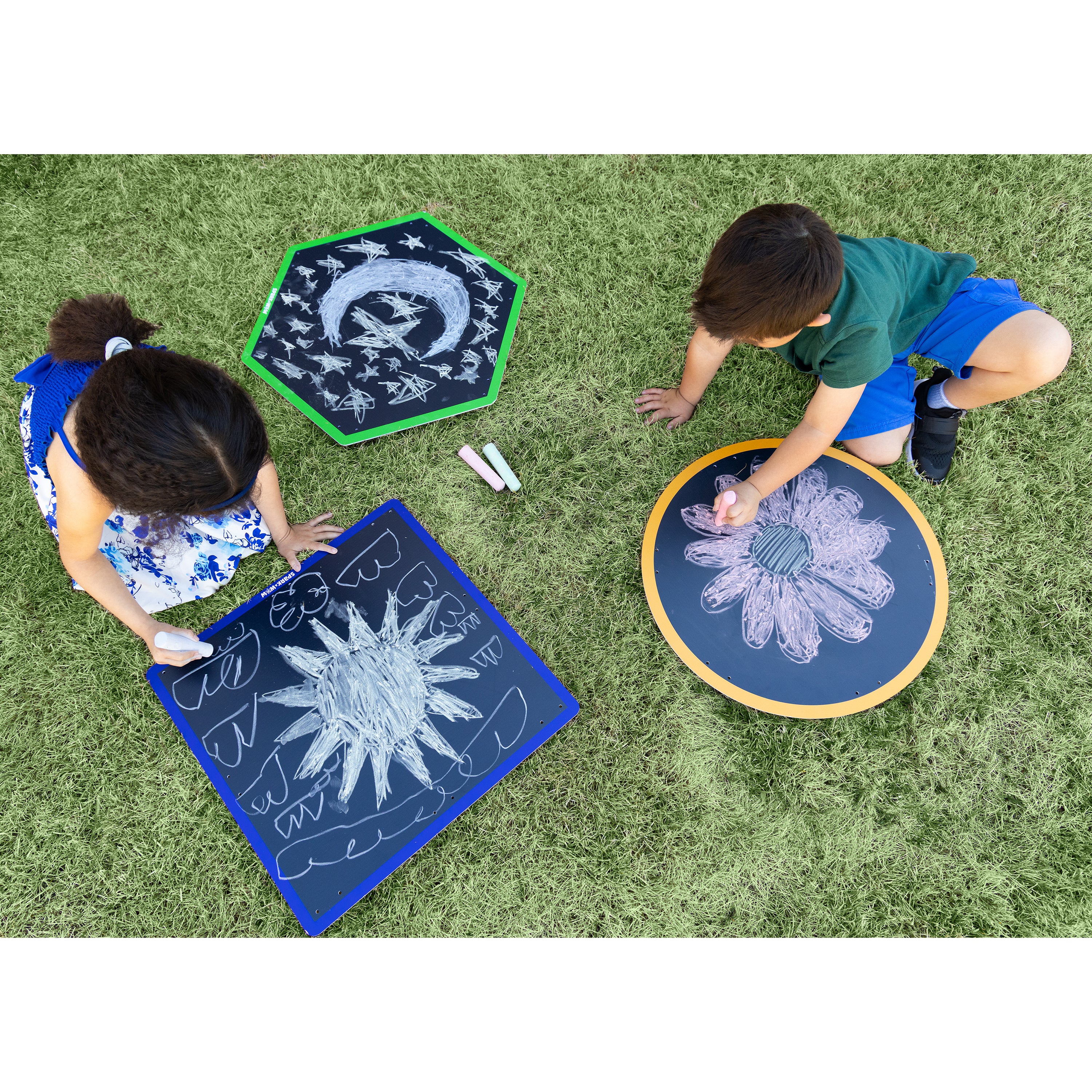 Two children playing with chalk on outdoor rugs with star and moon designs.