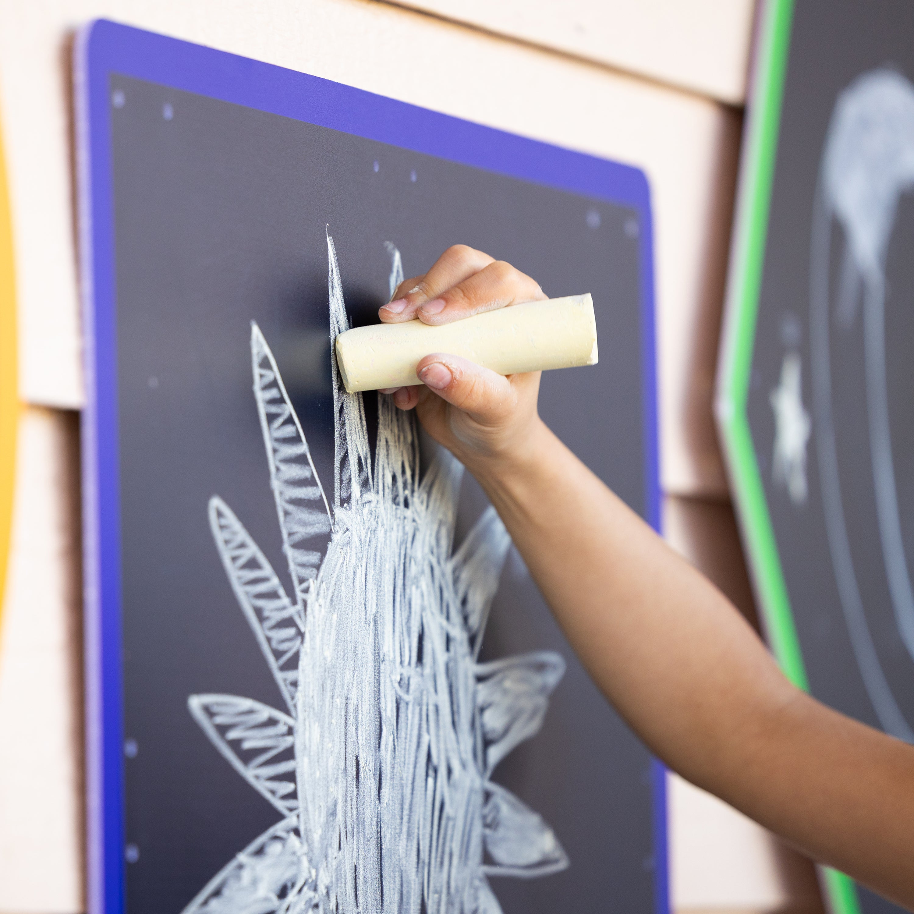 Hand holding a white chalk eraser over a blackboard with white chalk drawings.