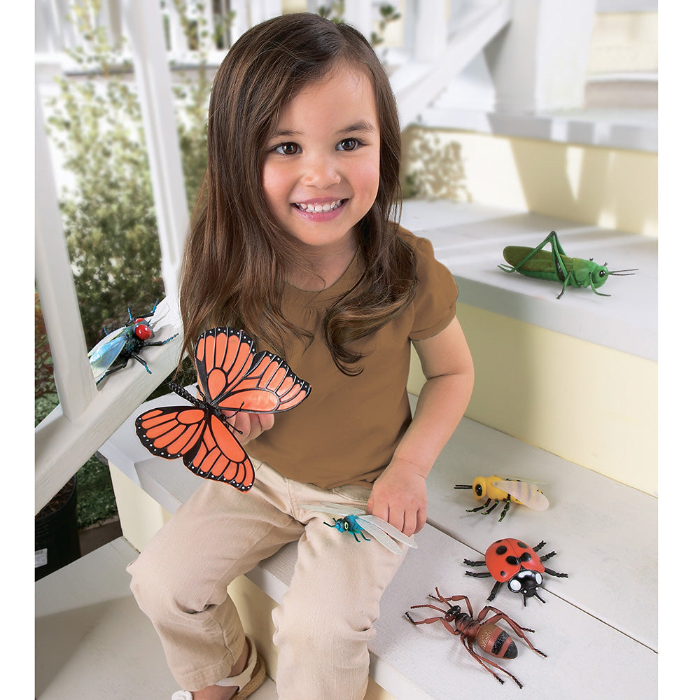 Child playing with toy insects on a white surface