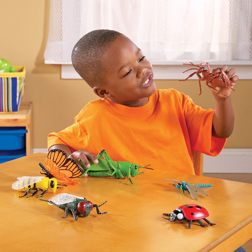 Child playing with toy insects on a table