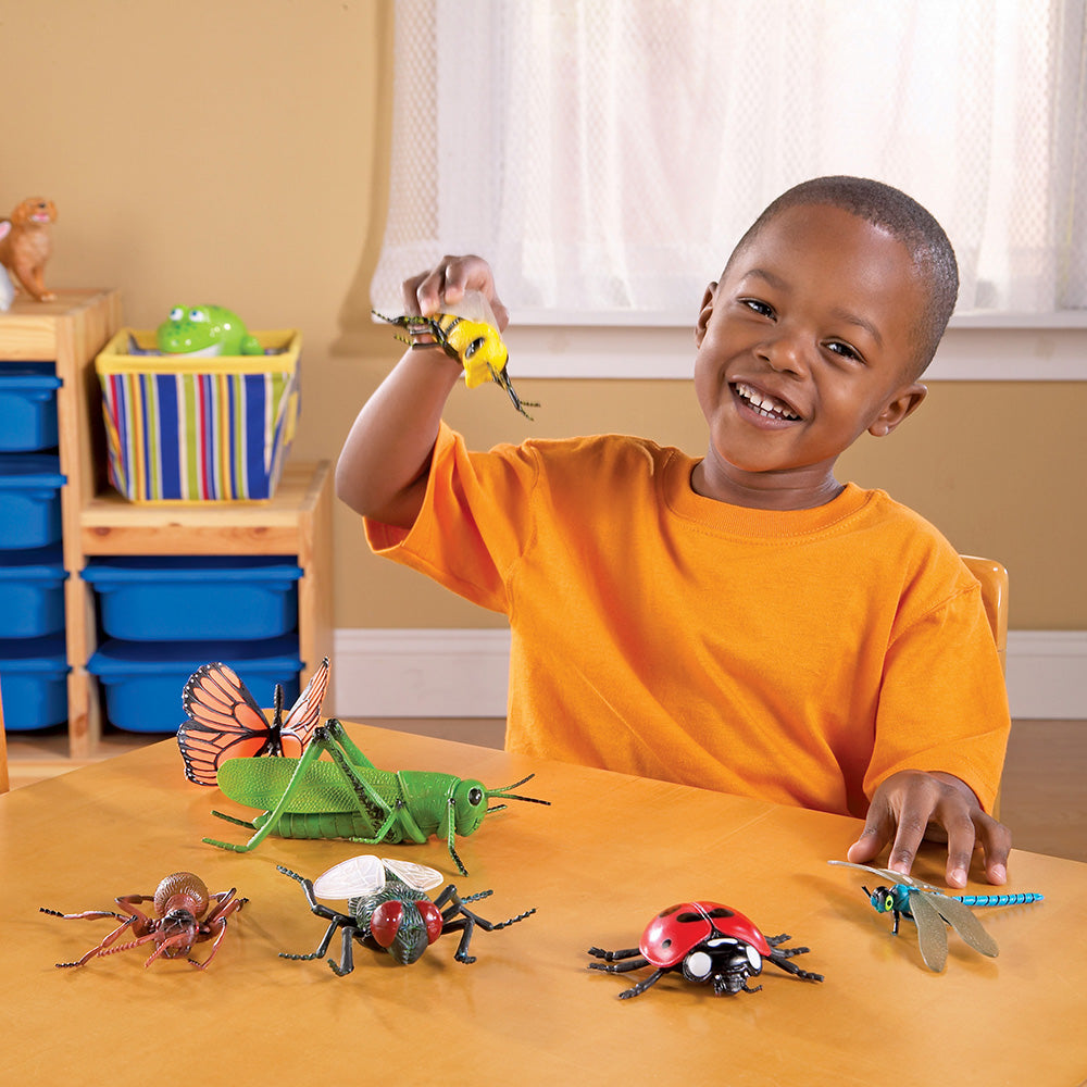 Child playing with toy insects on a table in a classroom setting