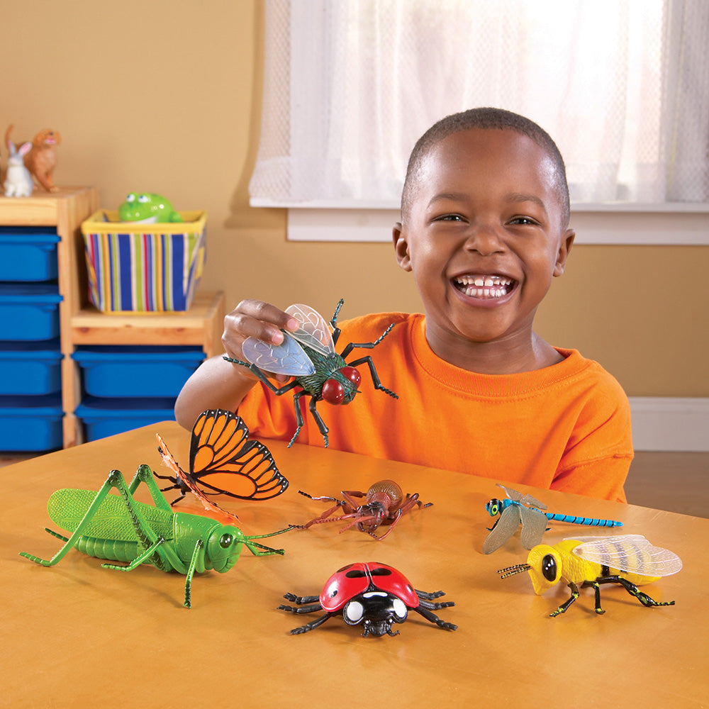 Child playing with toy insects on a table in a classroom setting