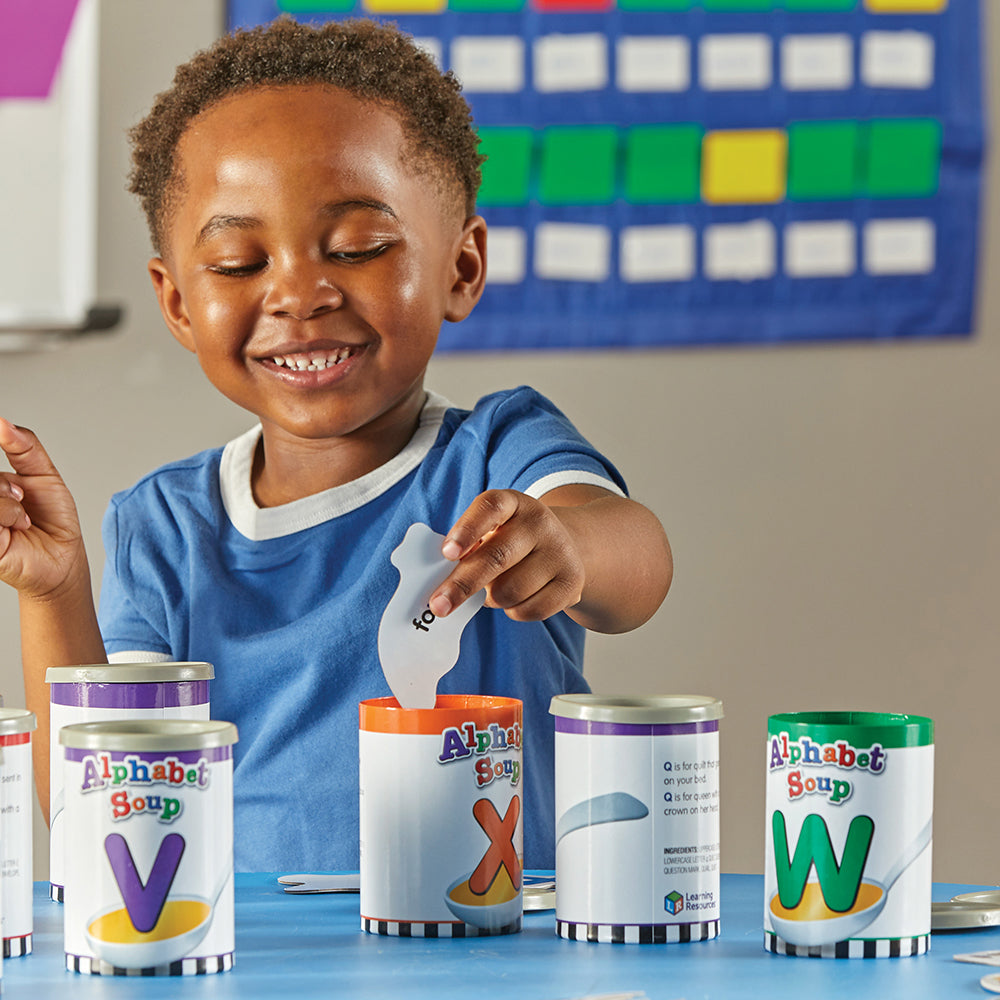 Kid in Classroom sorting Pictures in Alphabet Soup Cans