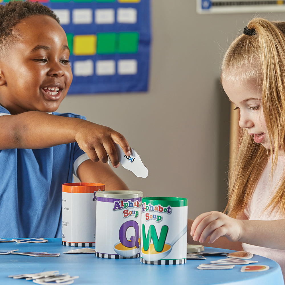 Two Kids in Classroom Engaging in Cooperative Play with Alphabet Soup Game