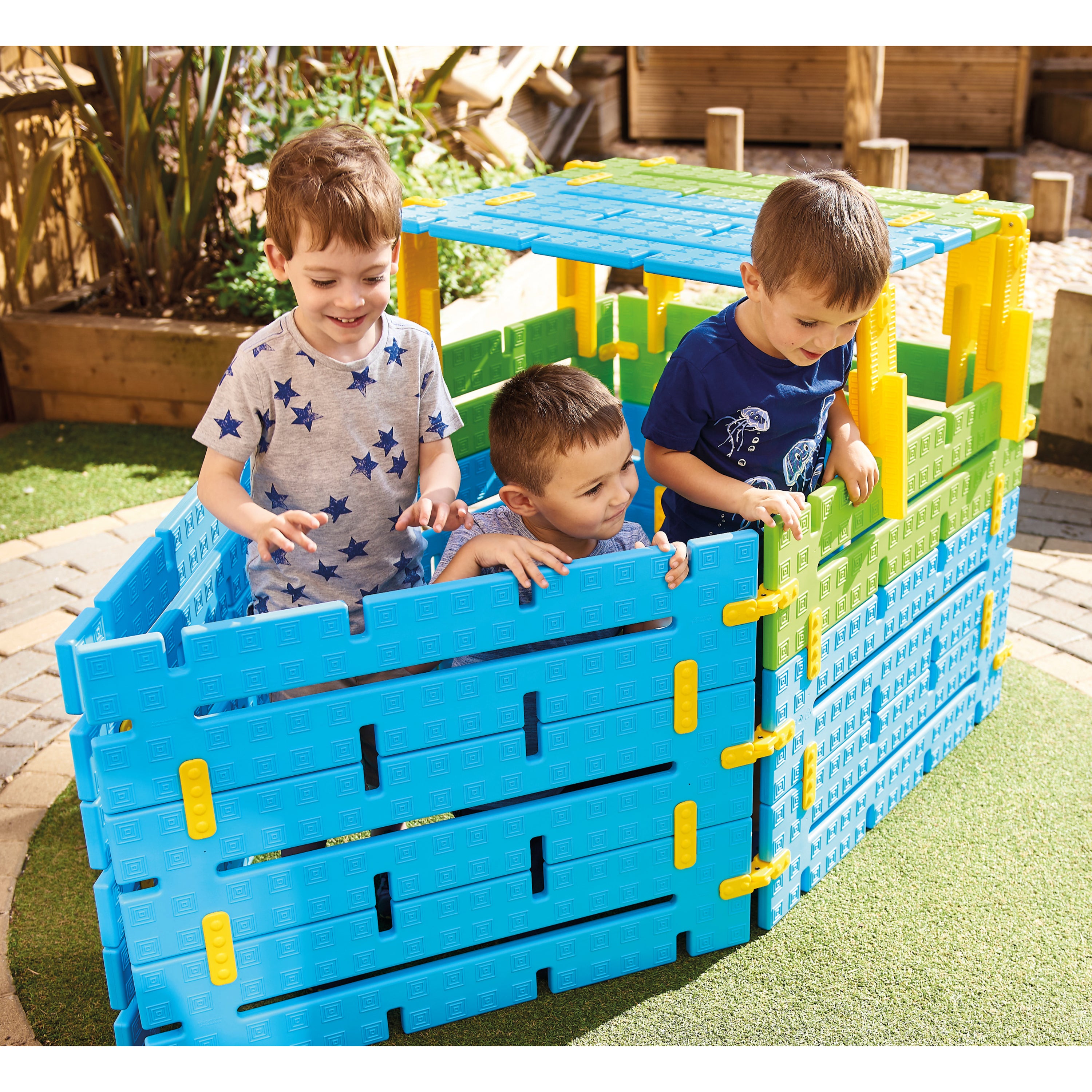 Three children playing with a colorful playpen structure outdoors.