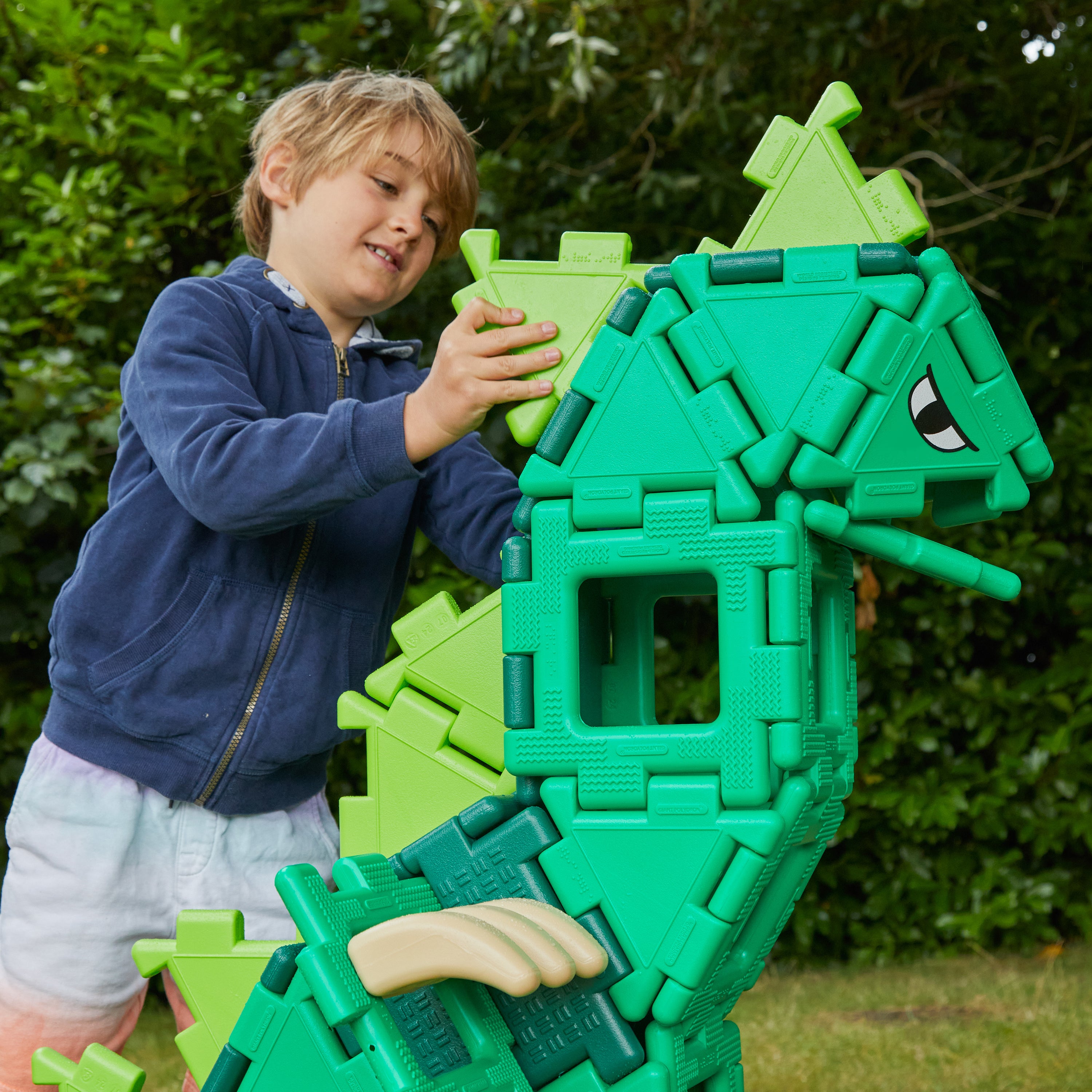 Child playing with a green toy structure outdoors