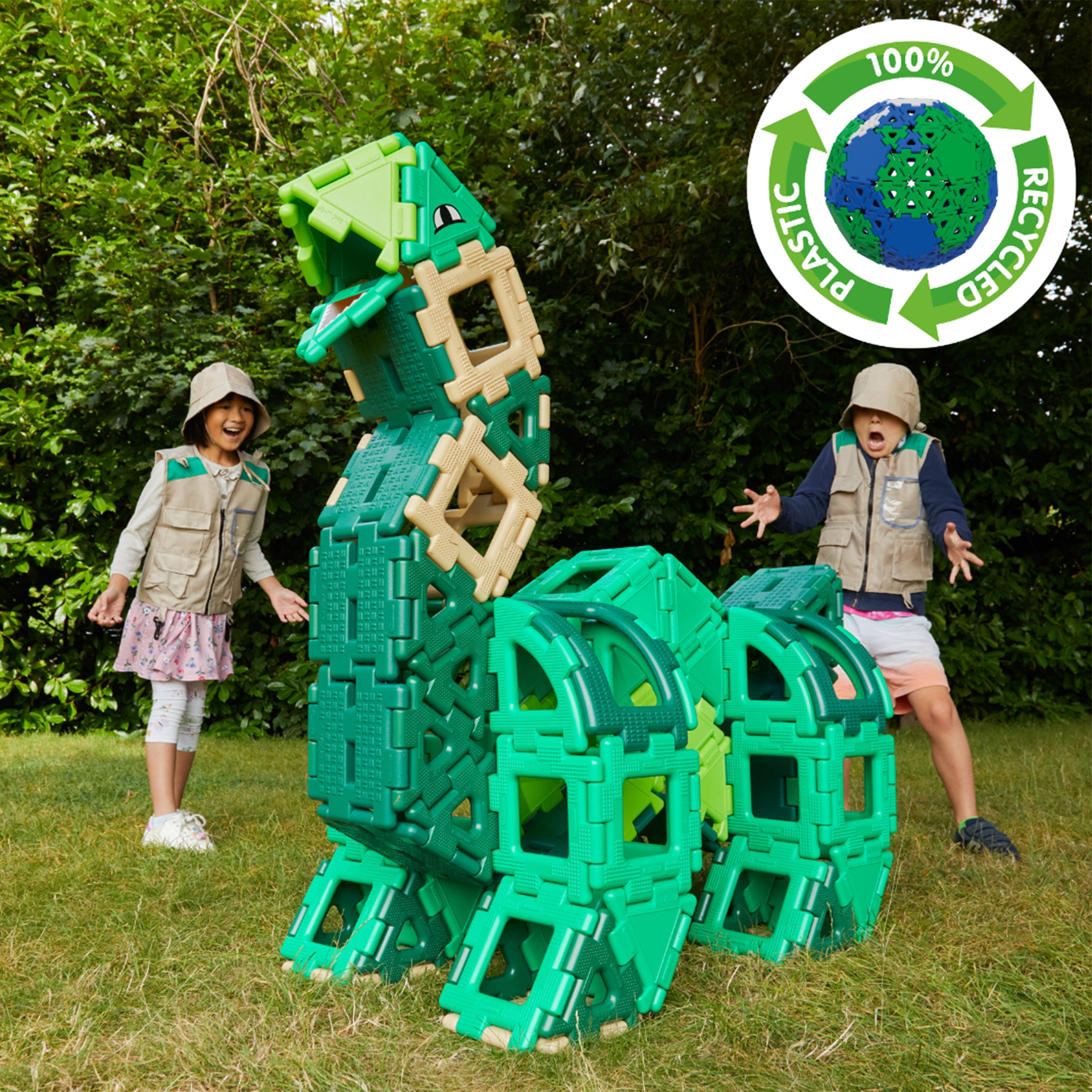Children playing with green dinosaur building blocks in a grassy area, with a recycling logo in the corner.