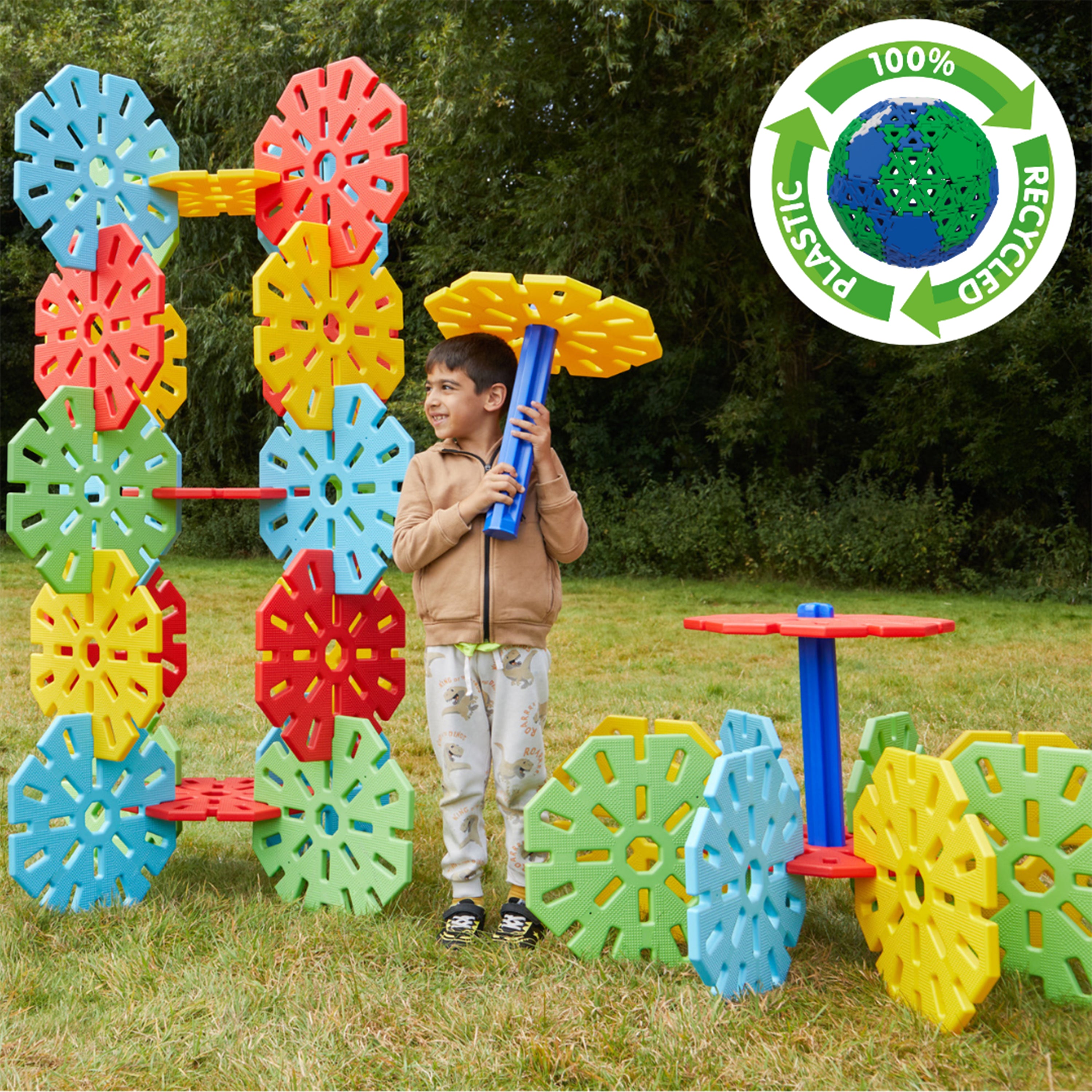 Child playing with colorful outdoor toy set in a grassy area, with a recycling logo in the corner.