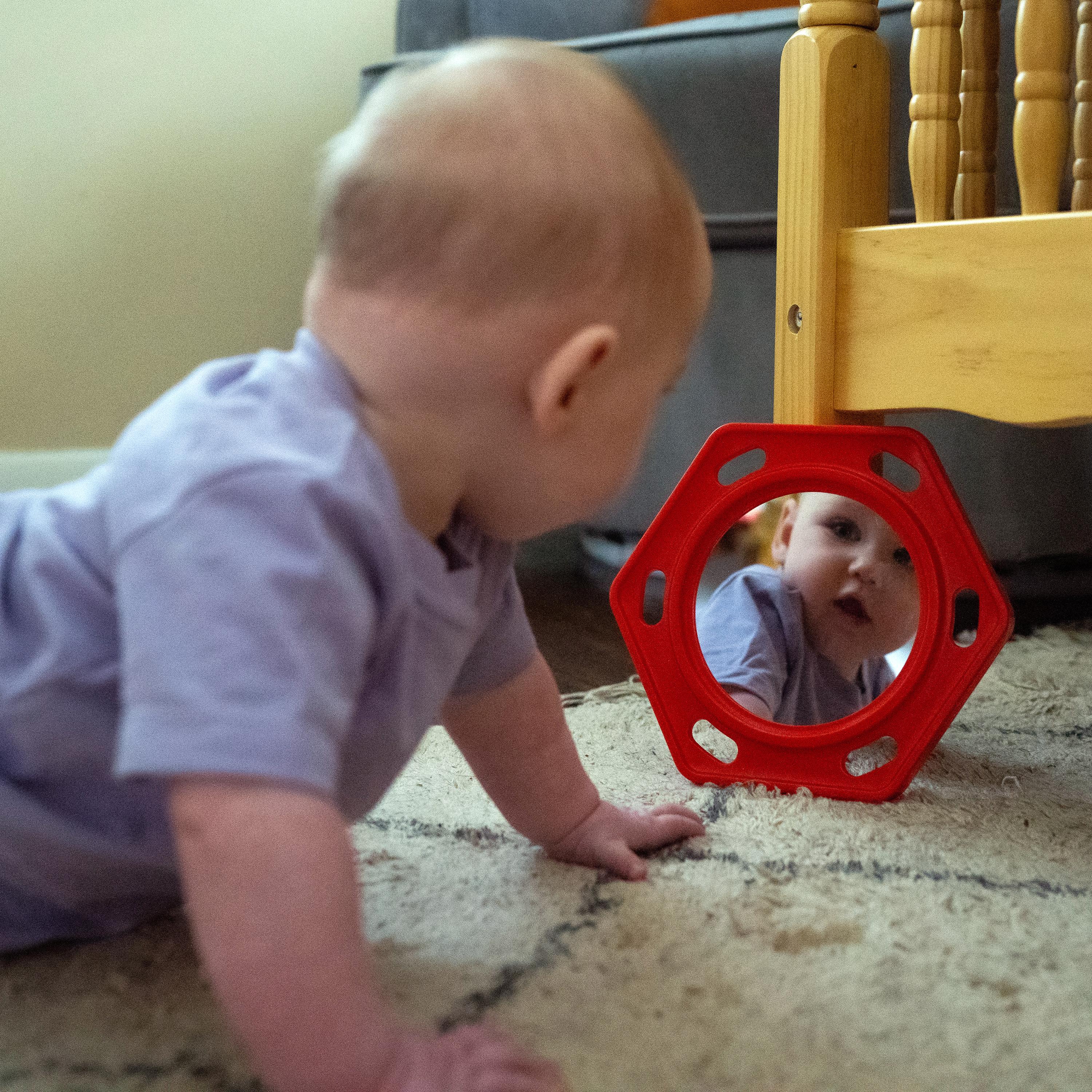 Baby crawling towards a red mirror on the floor