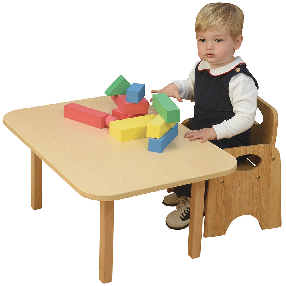 Toddler sitting in Classic Wooden Toddler Chair at table on white background