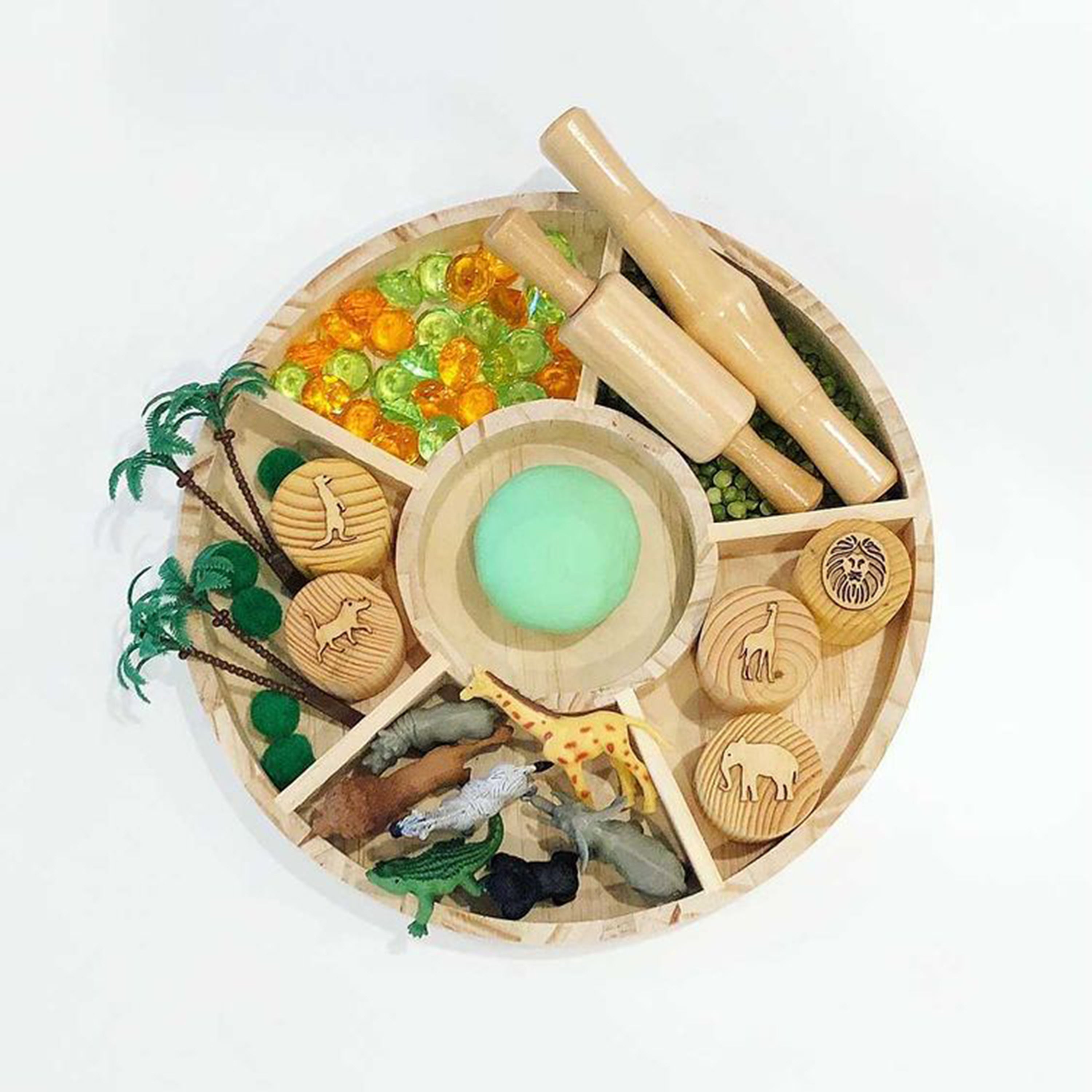 Wooden toy set with animals, plants, and a magnifying glass on a white background